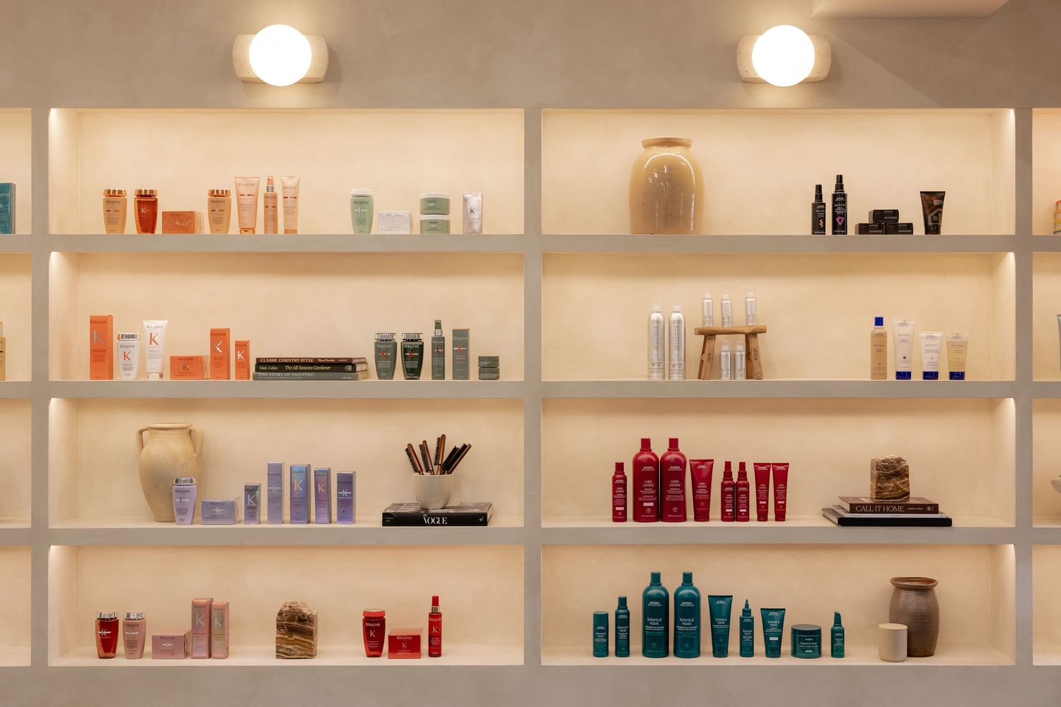 Long white shelving unit displaying colorful hair care products and beauty supplies in salon setting.