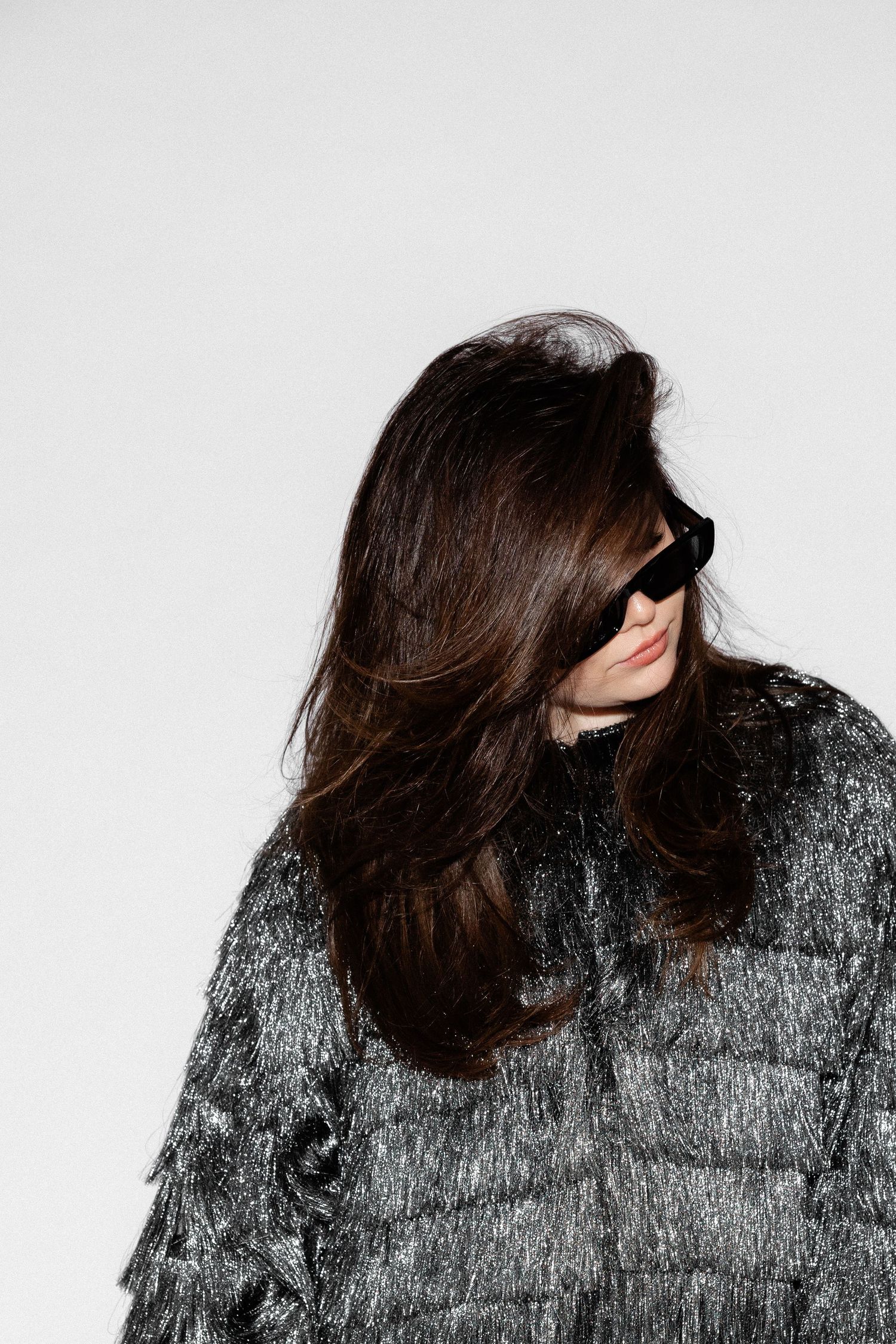 Artistic portrait with textured metallic jacket against white backdrop.