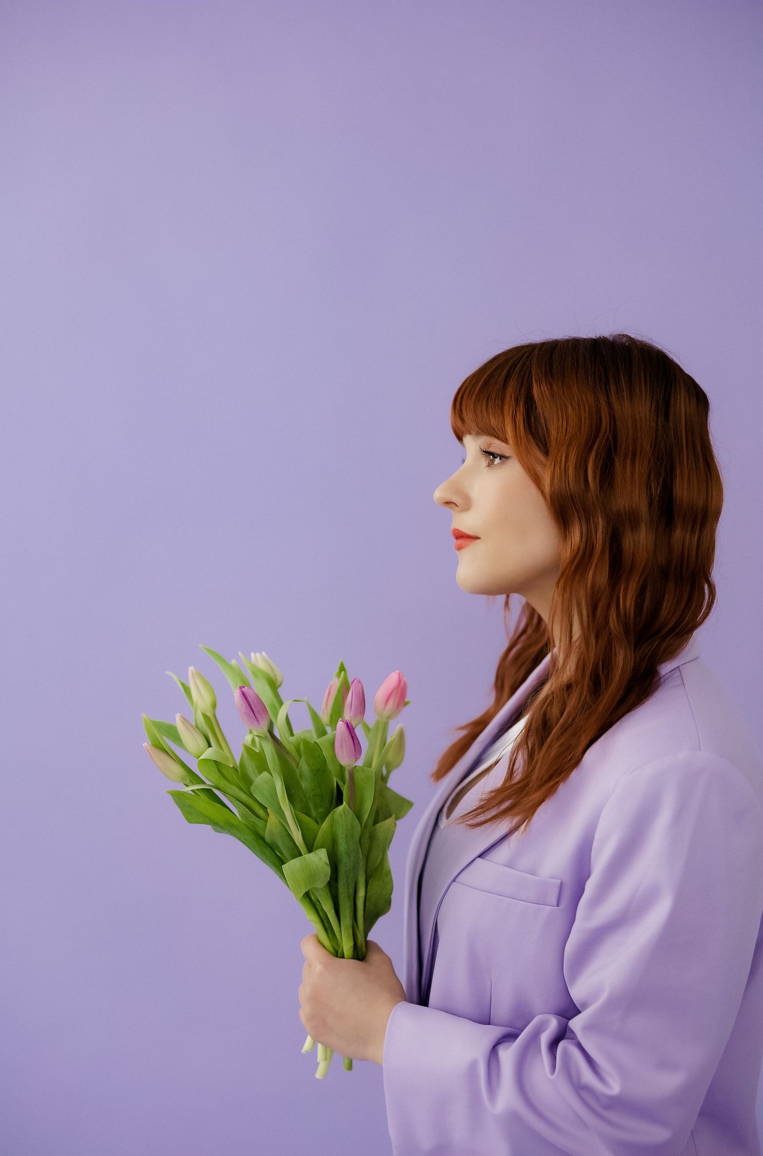Side profile shot with tulips against purple background showcasing spring fashion.