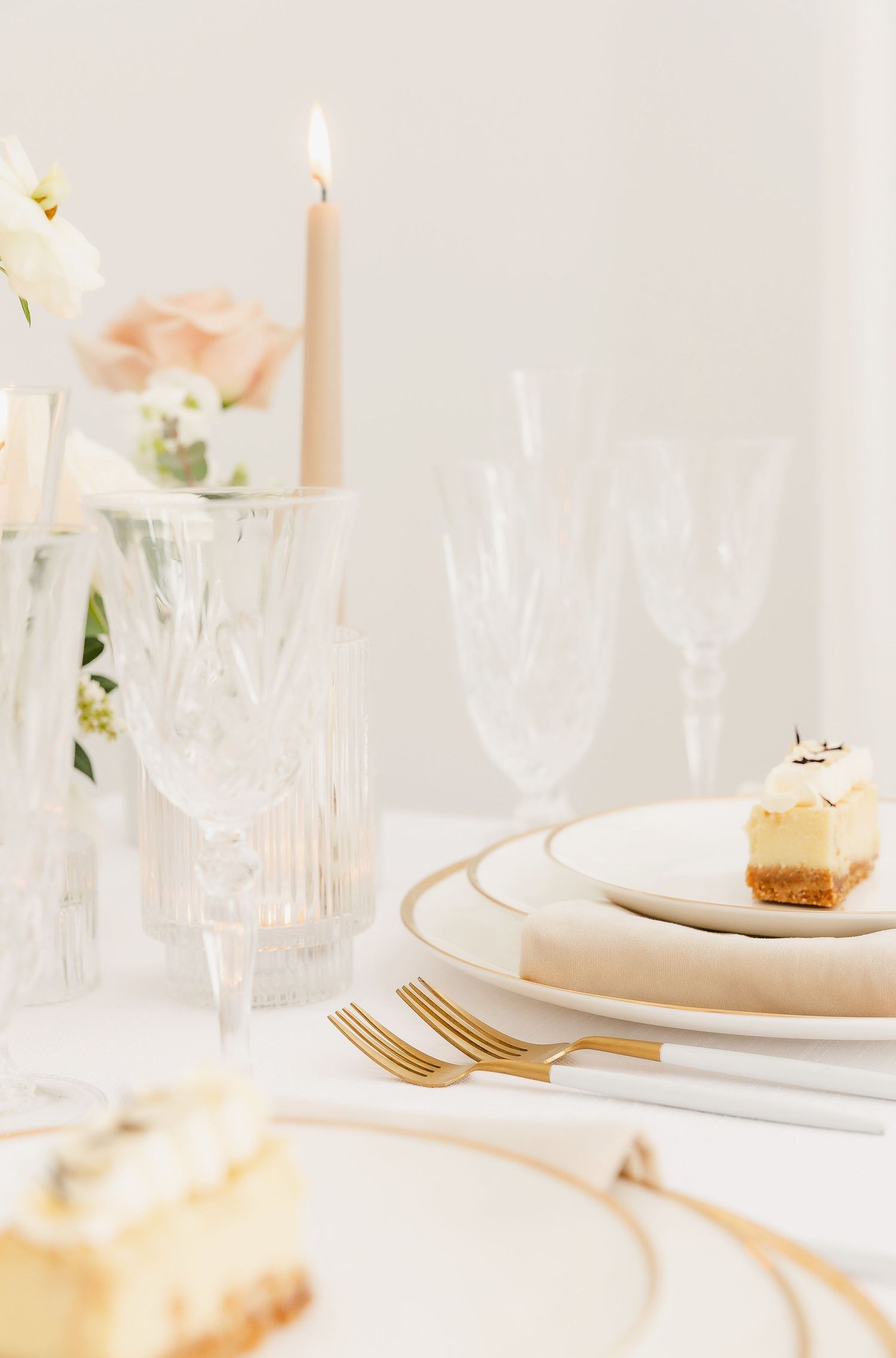 Ethereal table setting with crystal glassware, lit candles, and delicate floral arrangements.