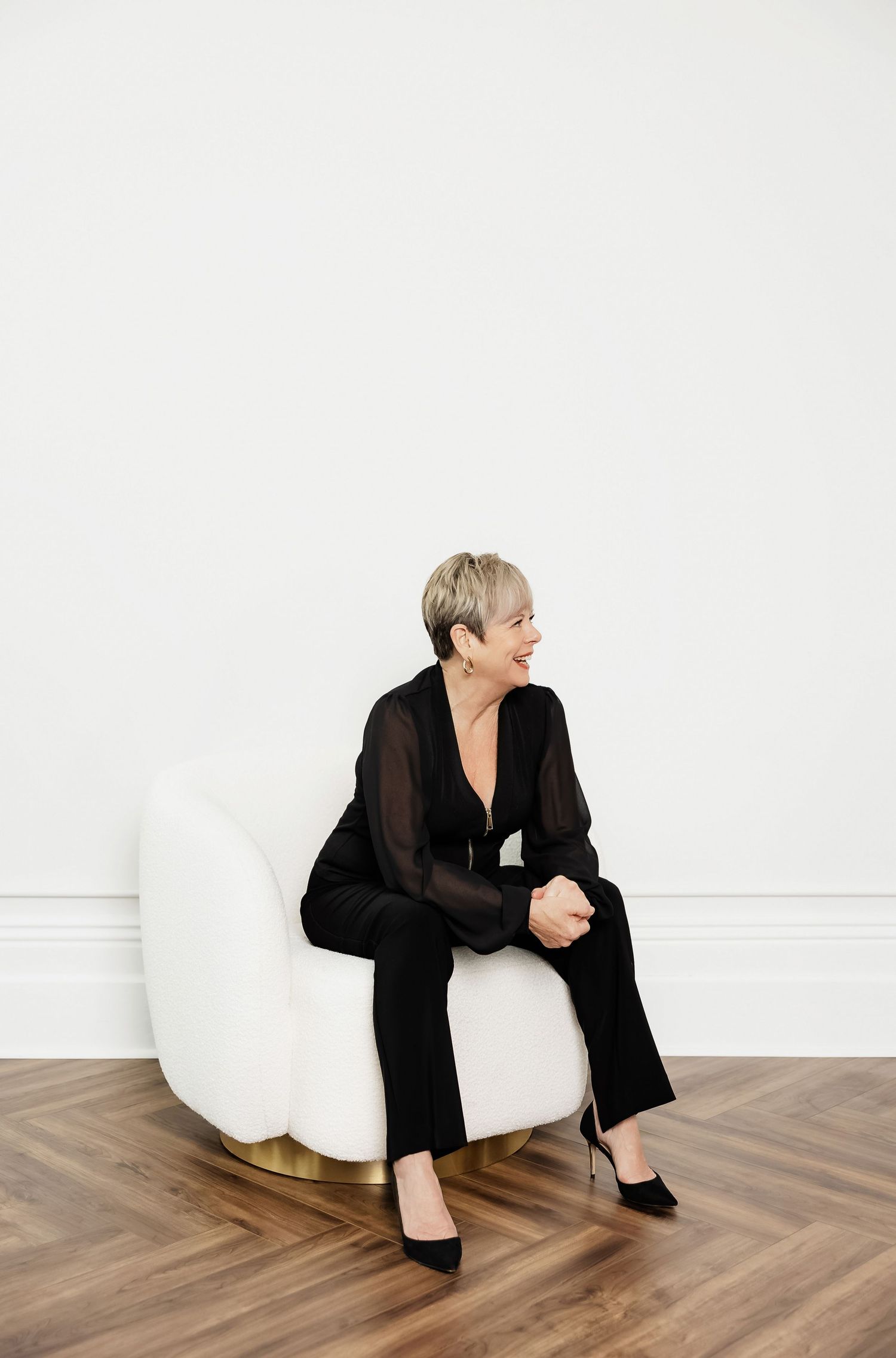 Model in black ensemble lounges on white bean bag chair showing relaxed poses.