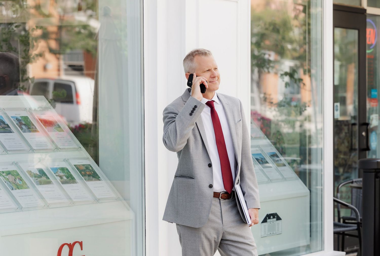 Business professional in grey suit making phone call outside office building.