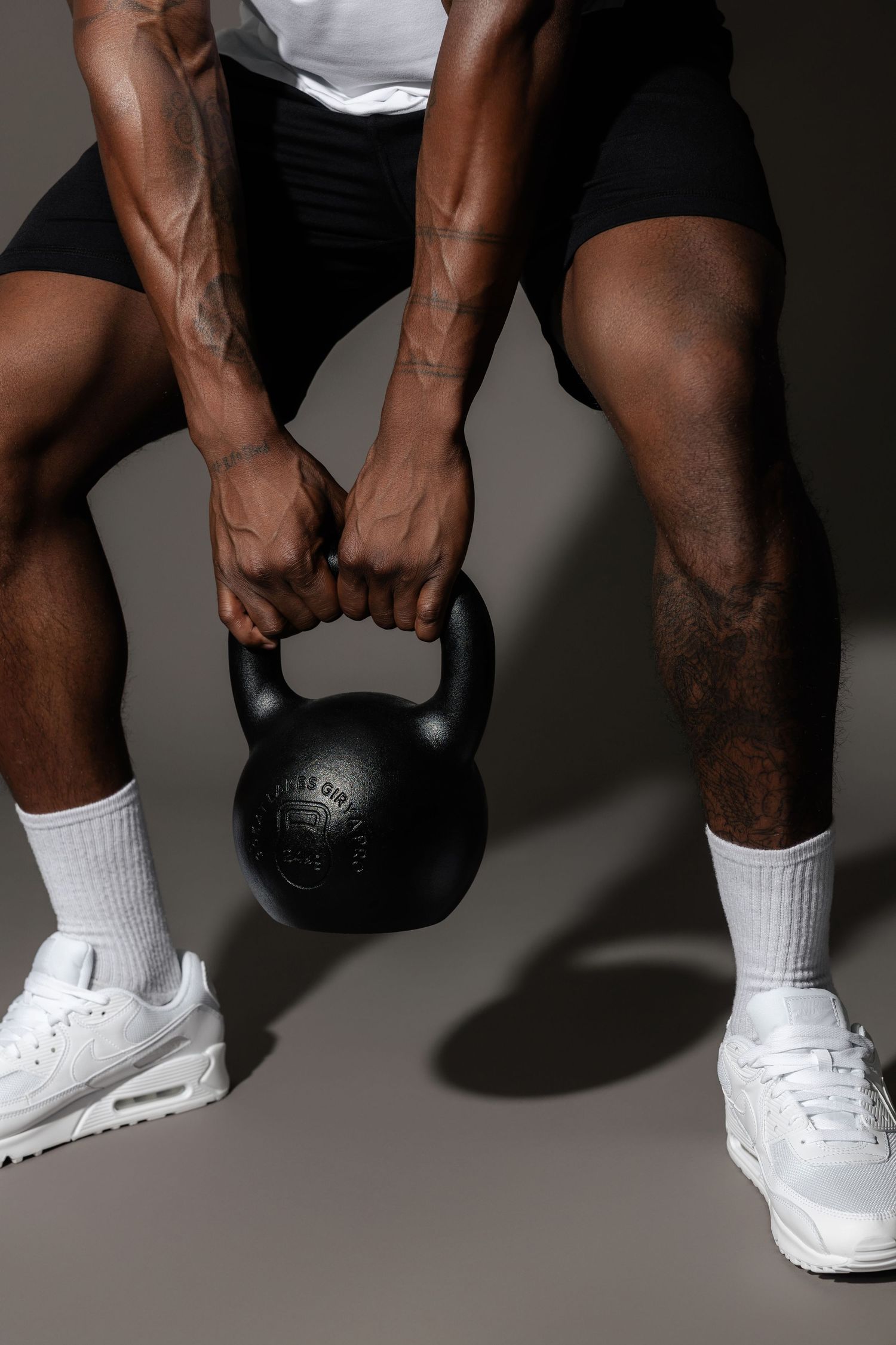 White sneakers and legs shown during kettlebell workout on studio floor.