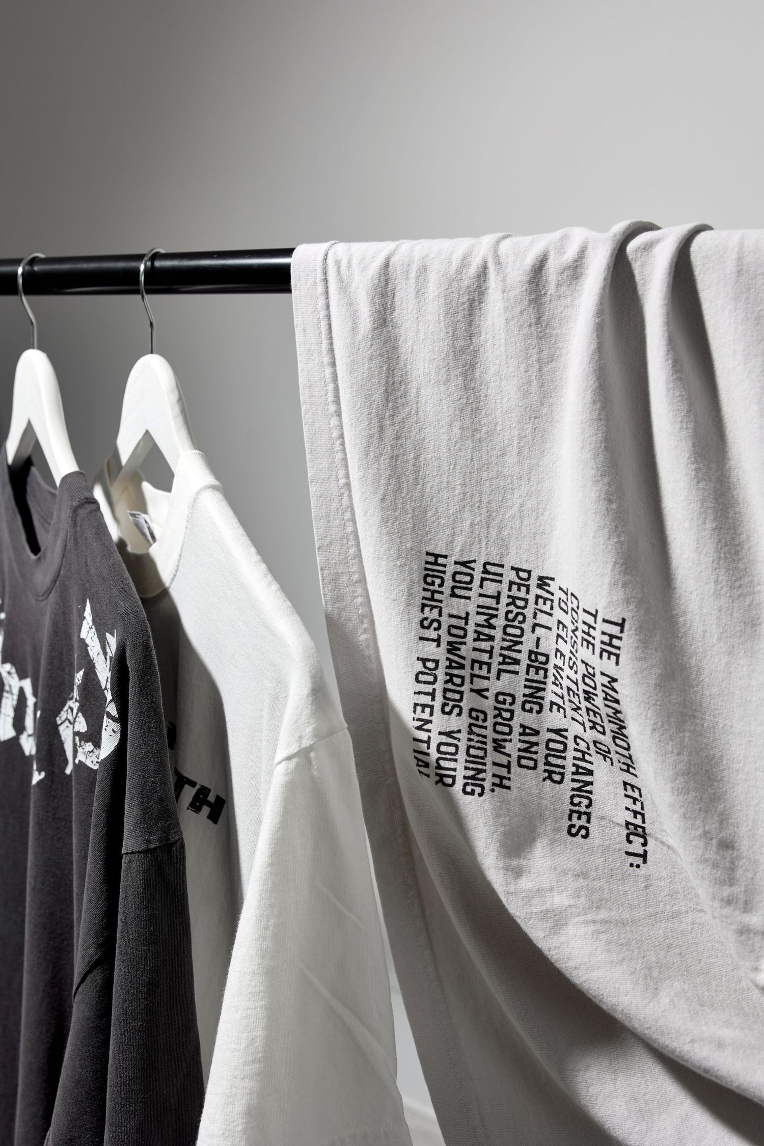 Row of white and black clothing hanging on garment rack with text details visible.