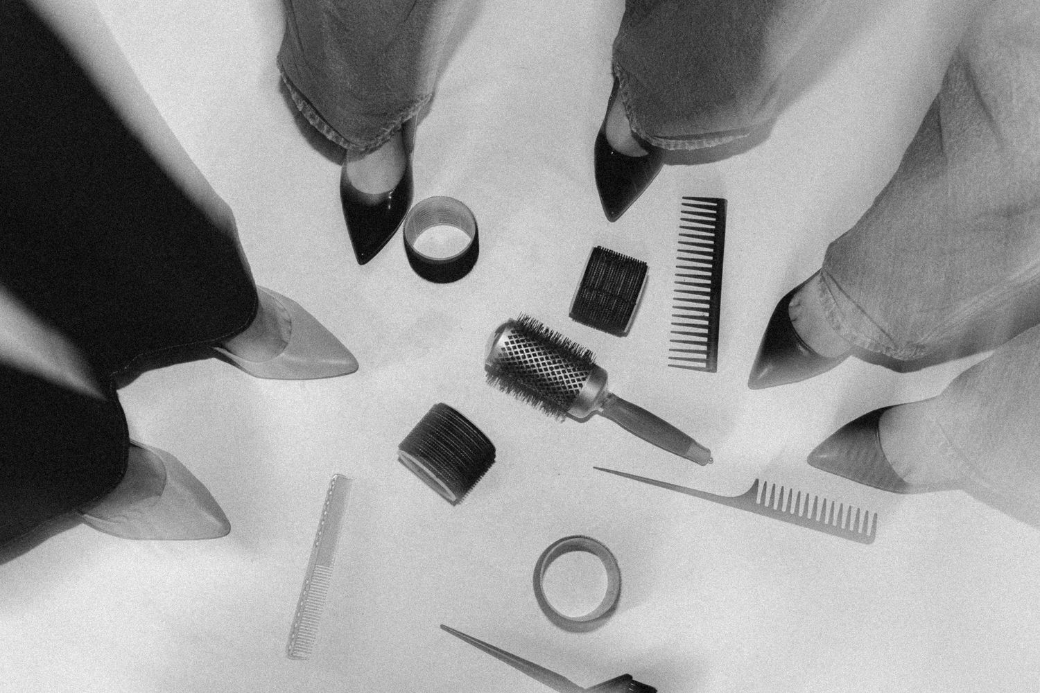 Overhead view of hair styling tools and accessories arranged on white surface.