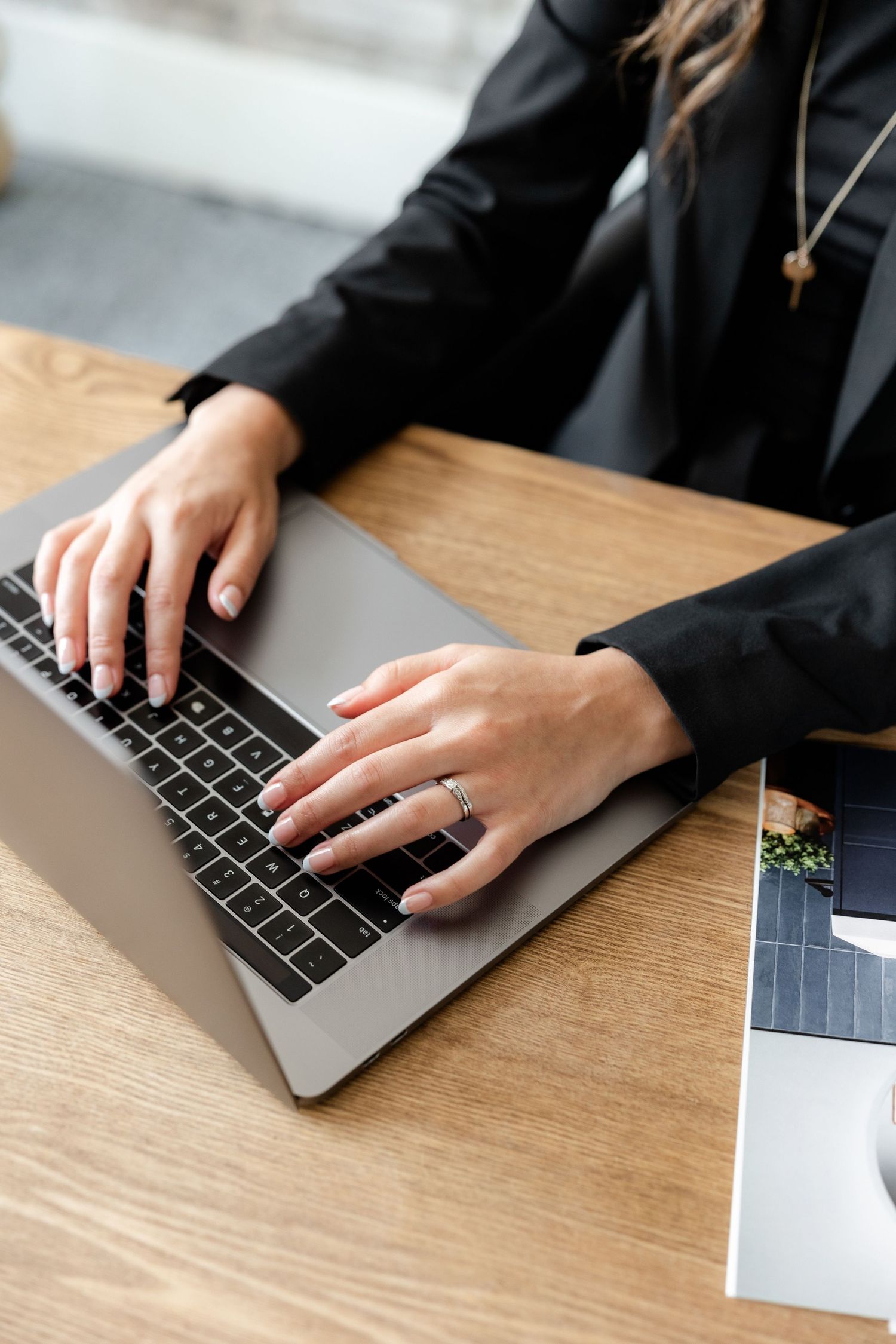 Close-up shots of hands typing on MacBook keyboard on wooden desk surface.