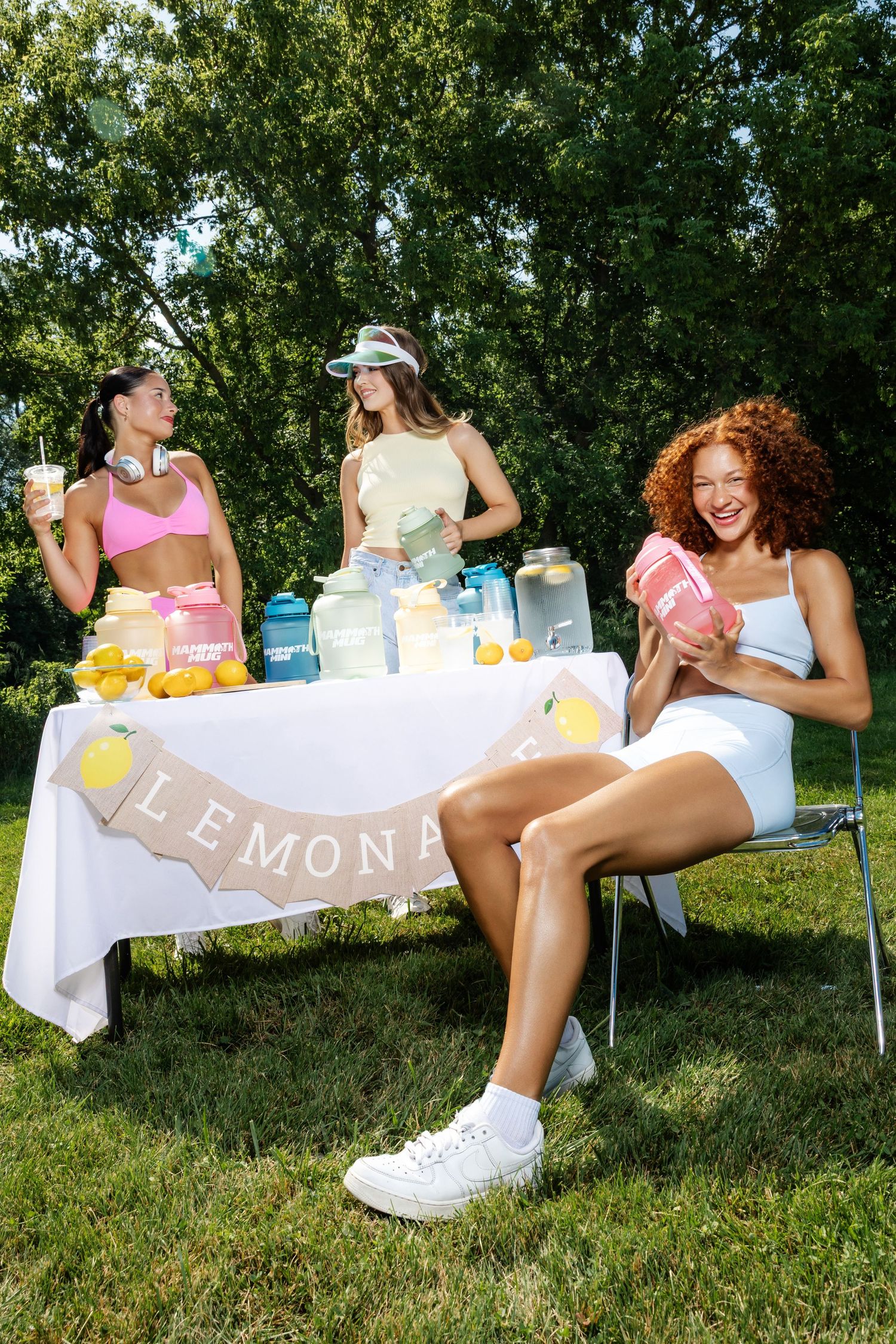 Summer outdoor gathering with drinks and lemons displayed on a white table with banner.