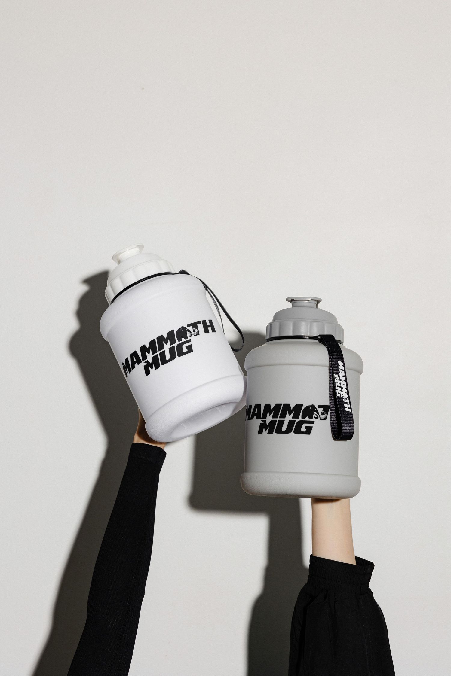 Hands holding white branded drink containers against a minimalist white background.