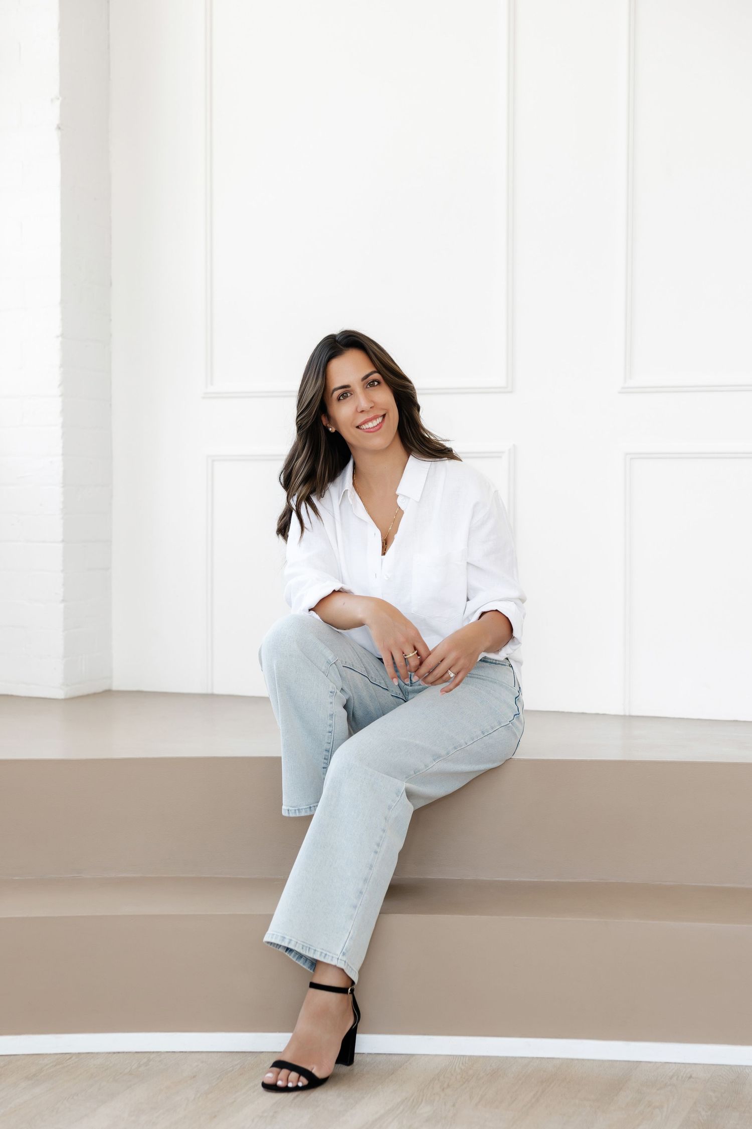 Person in casual outfit lounges on built-in bench against white wall.