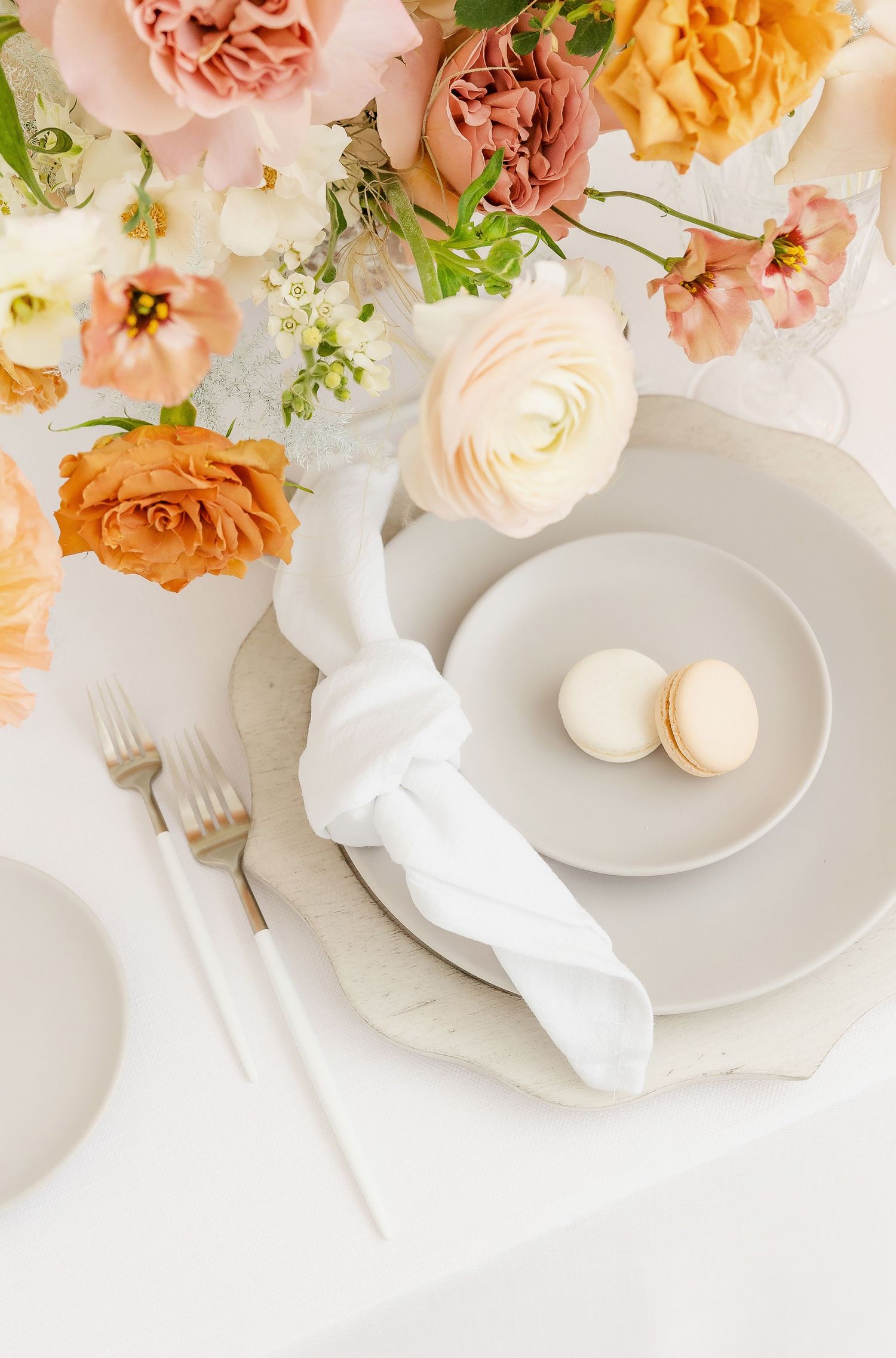 Elegant place setting with blush roses and white plates on a marble surface.