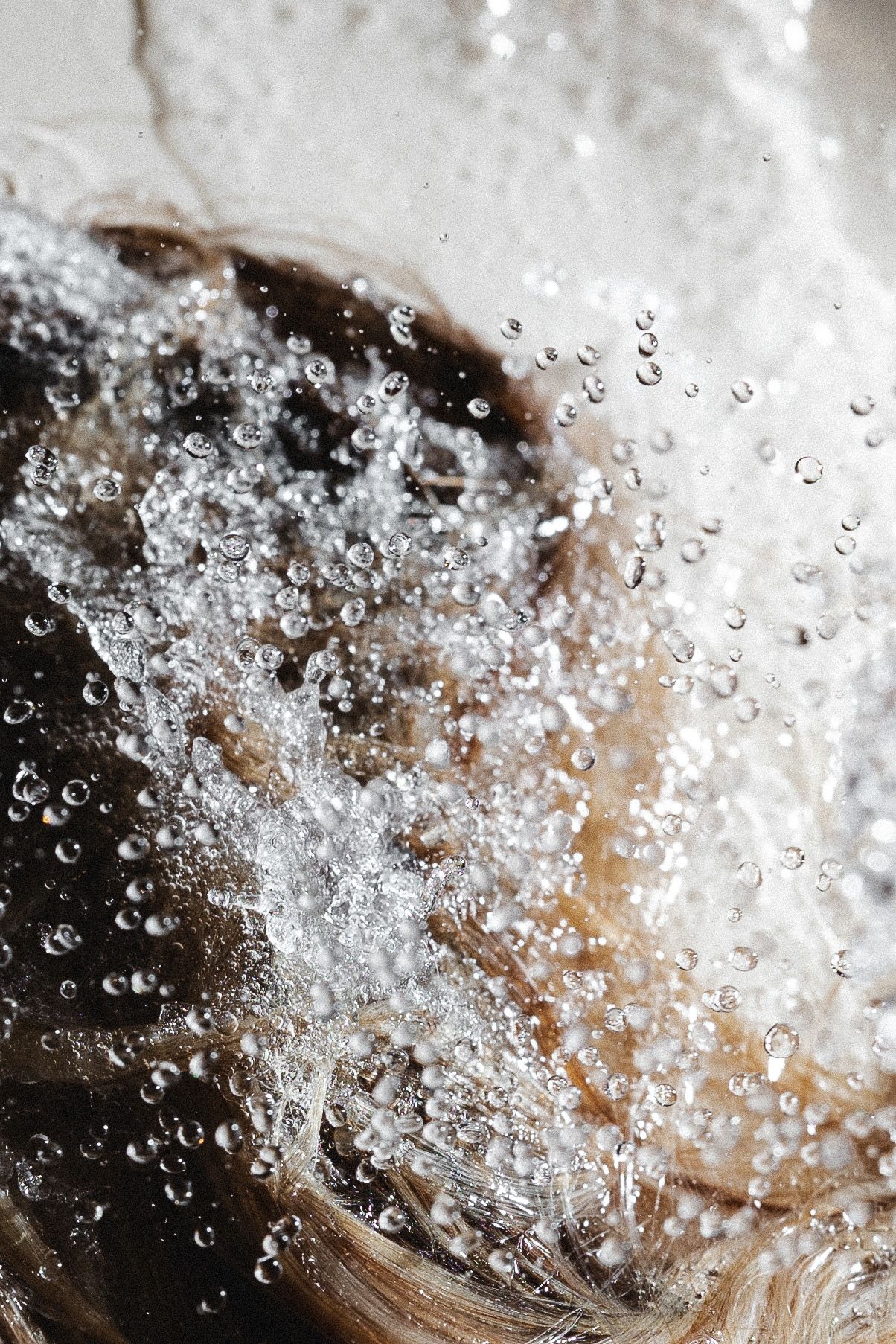Close-up of water droplets and bubbles splashing during hair washing.