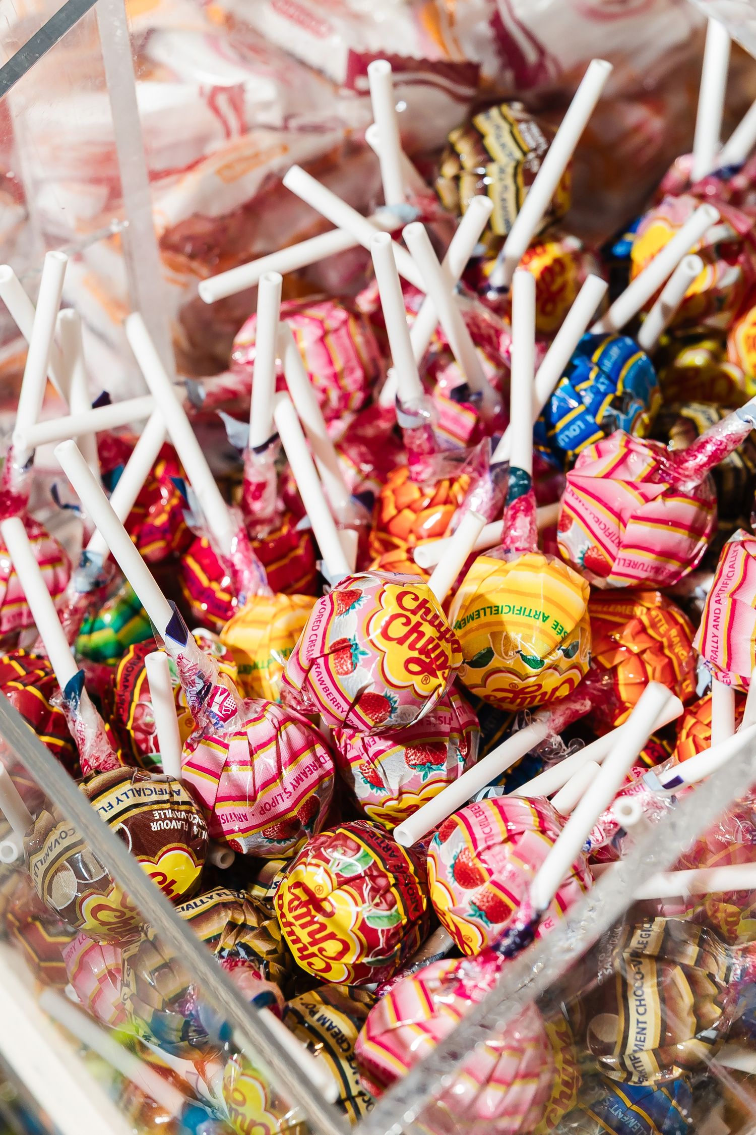 Assorted wrapped lollipops with colorful wrappers and white sticks.