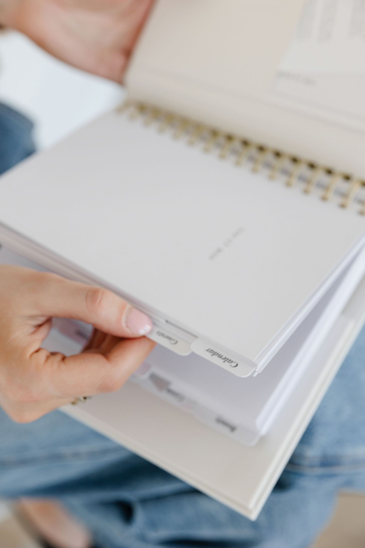 Close-up of hands turning pages in white spiral-bound planner.