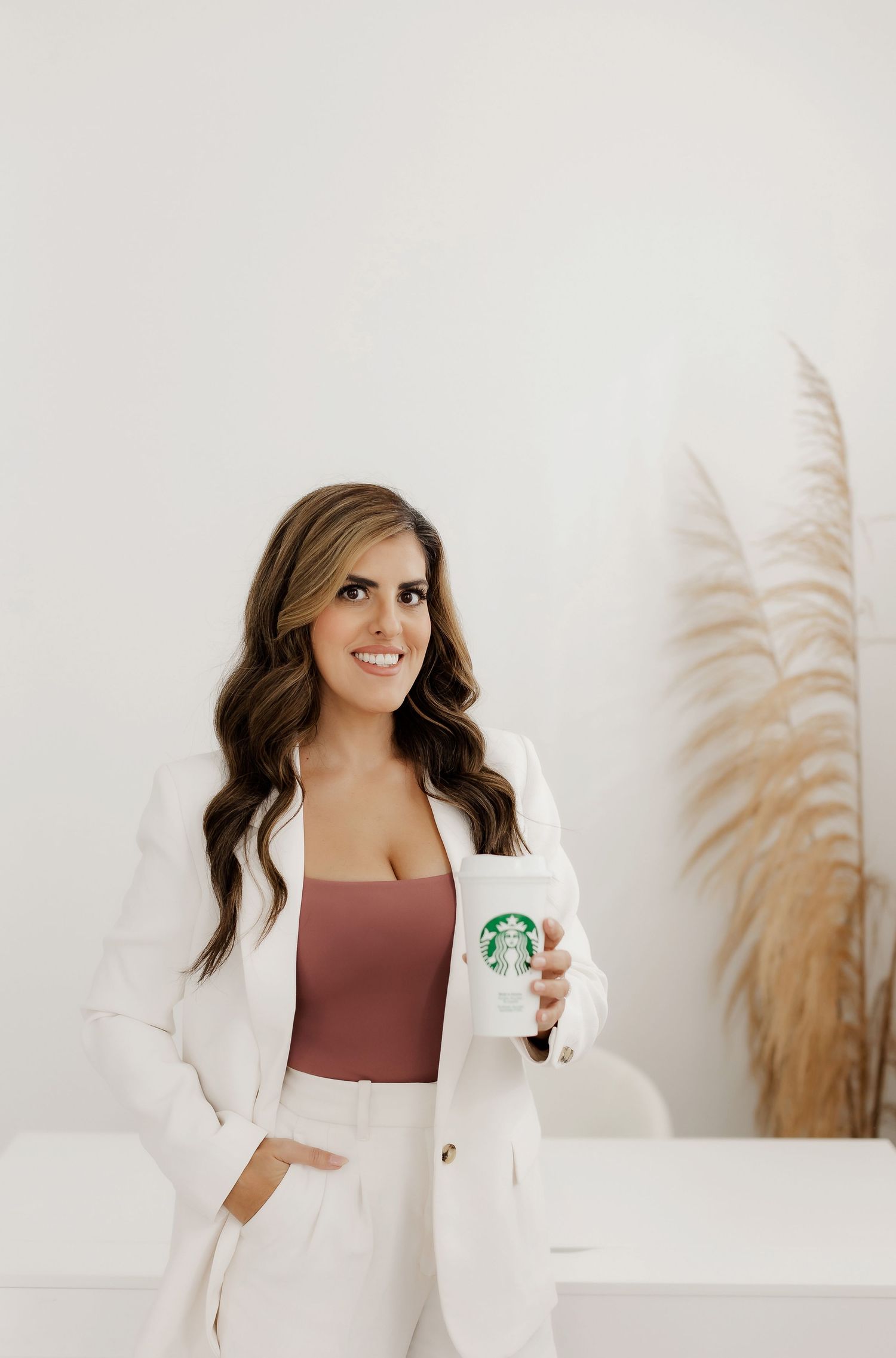 Business professional holding Starbucks cup in modern white office setting.
