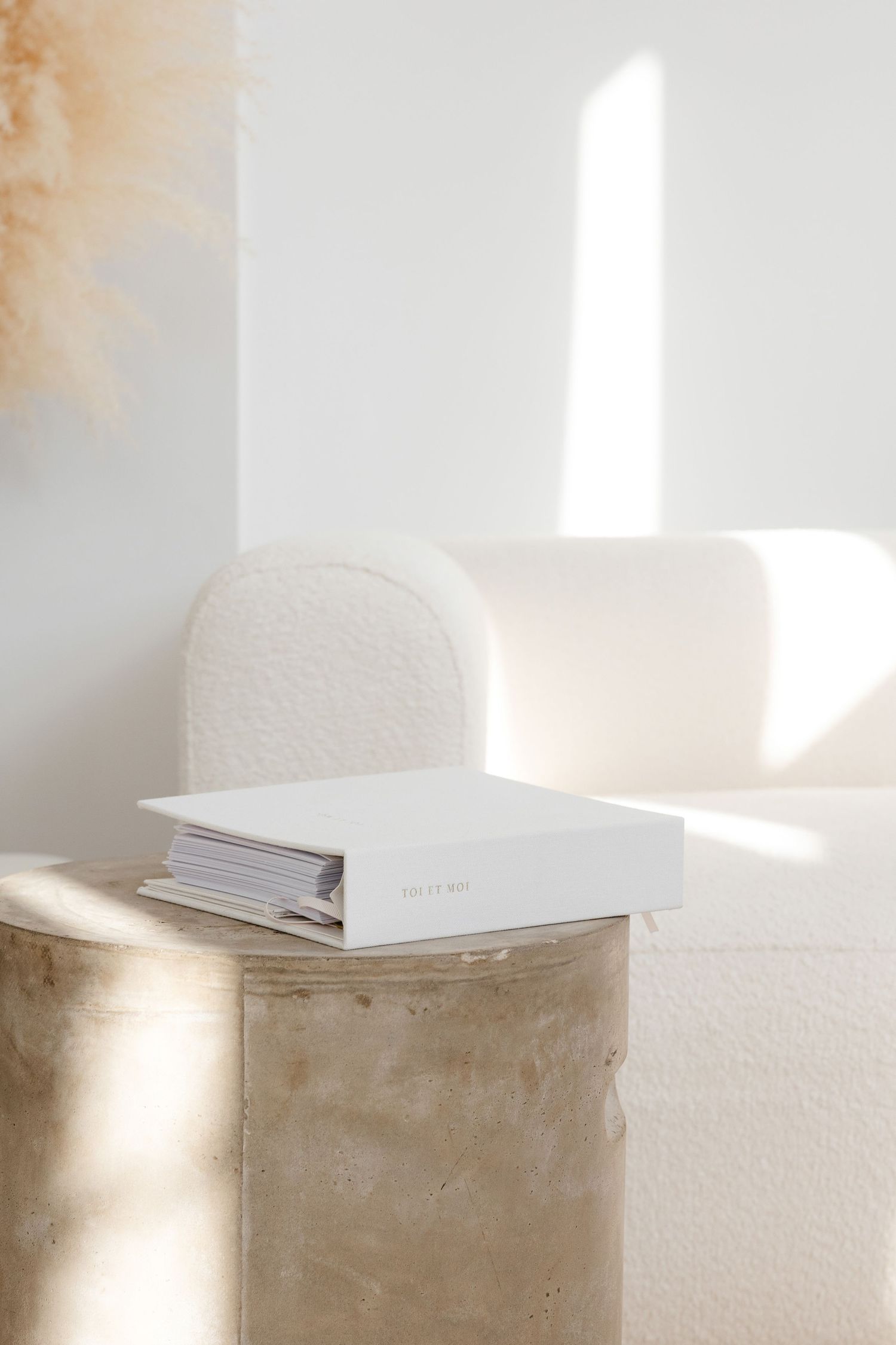 Minimalist white stationery displayed on a textured beige surface with soft natural lighting.
