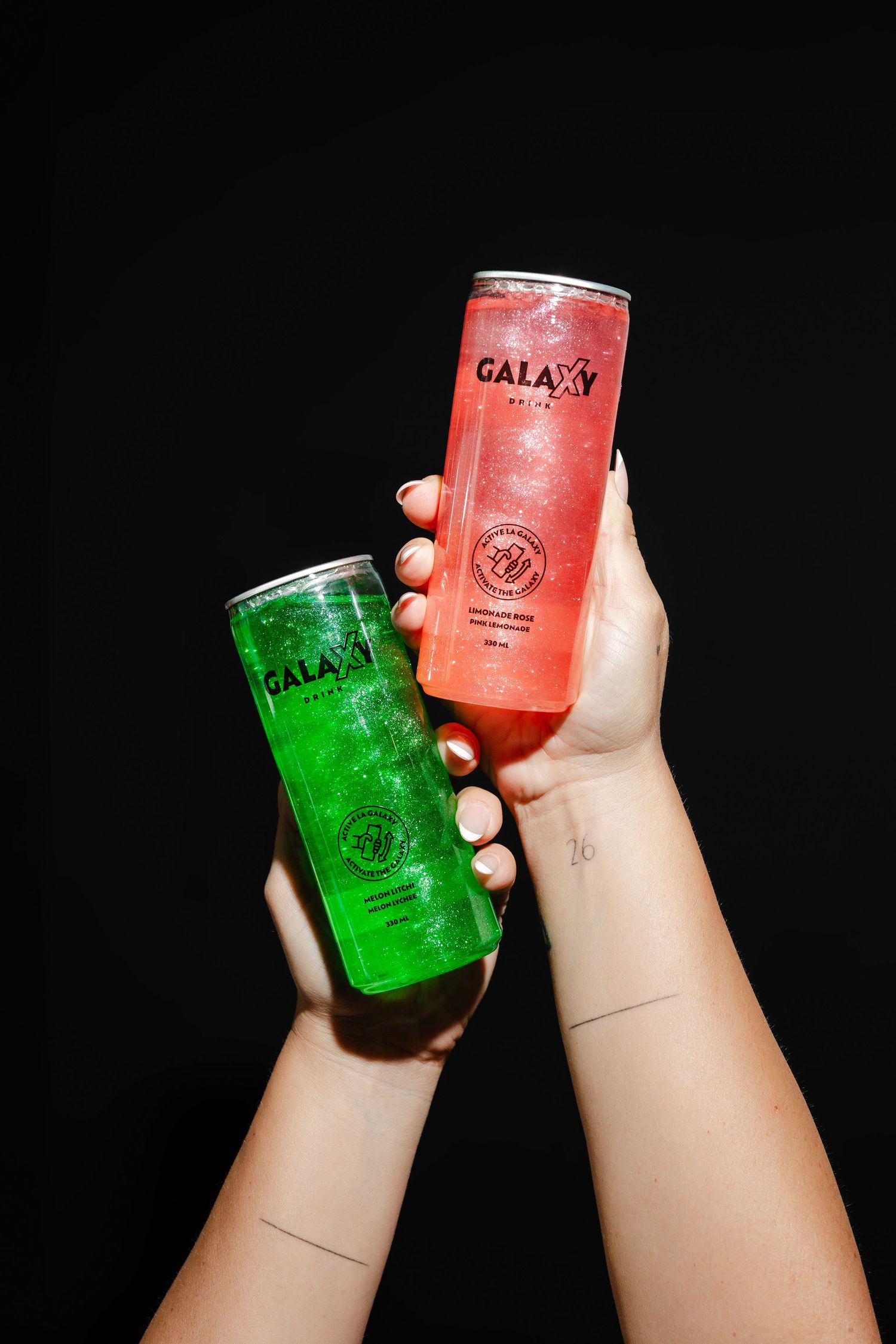 Hands holding colorful glowing drinks against a dark background.