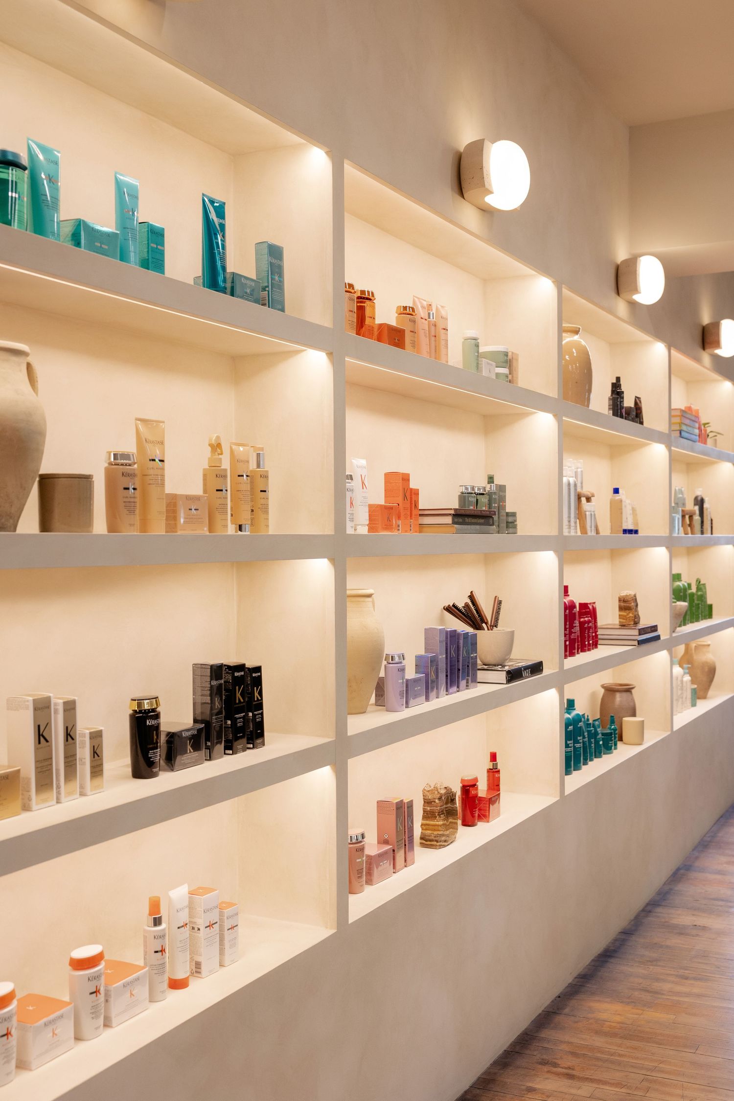 Extensive wall-mounted shelving displaying professional hair care products in modern salon interior.