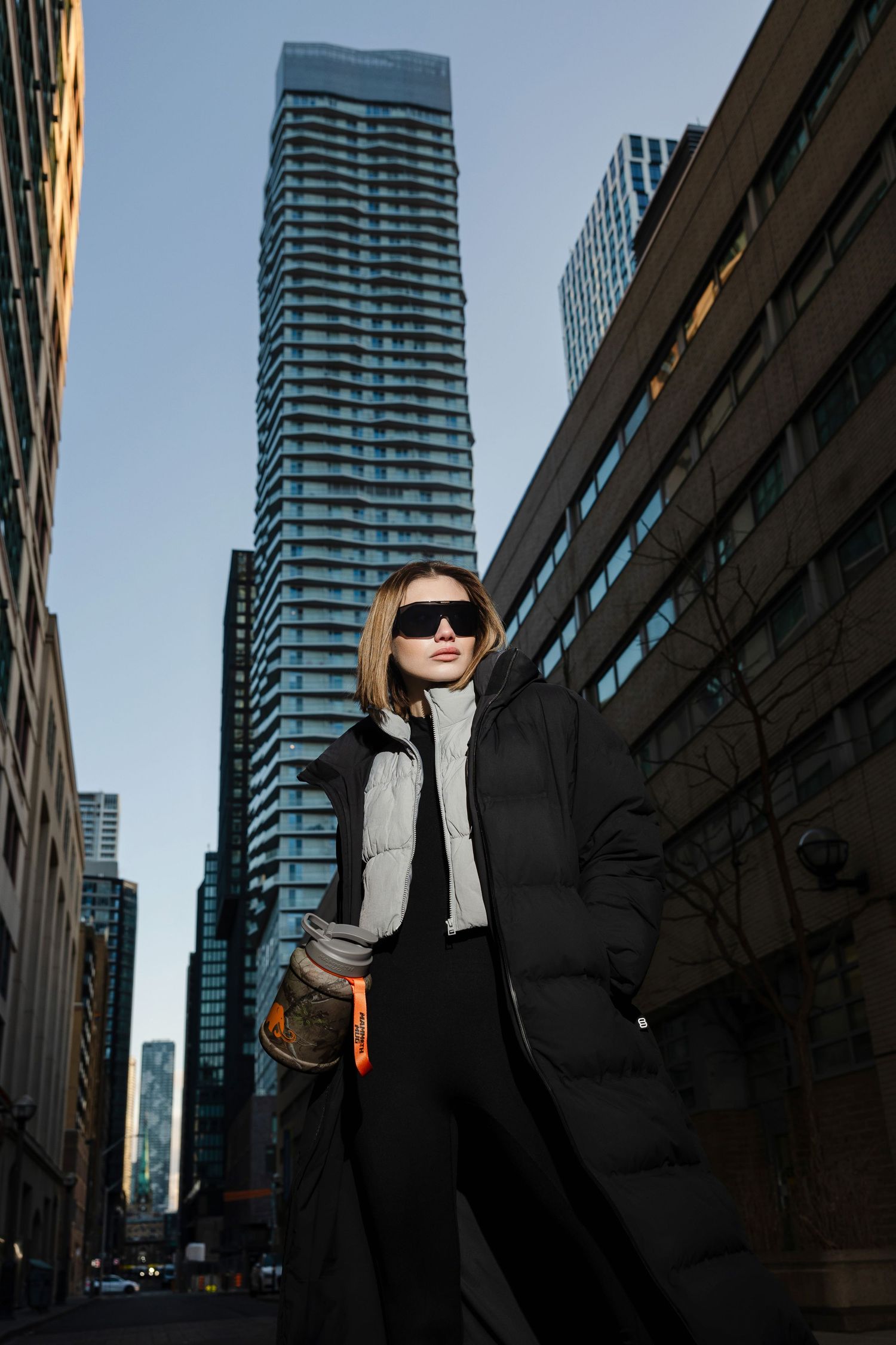 People in black clothing pose dramatically against urban buildings and skyscrapers.