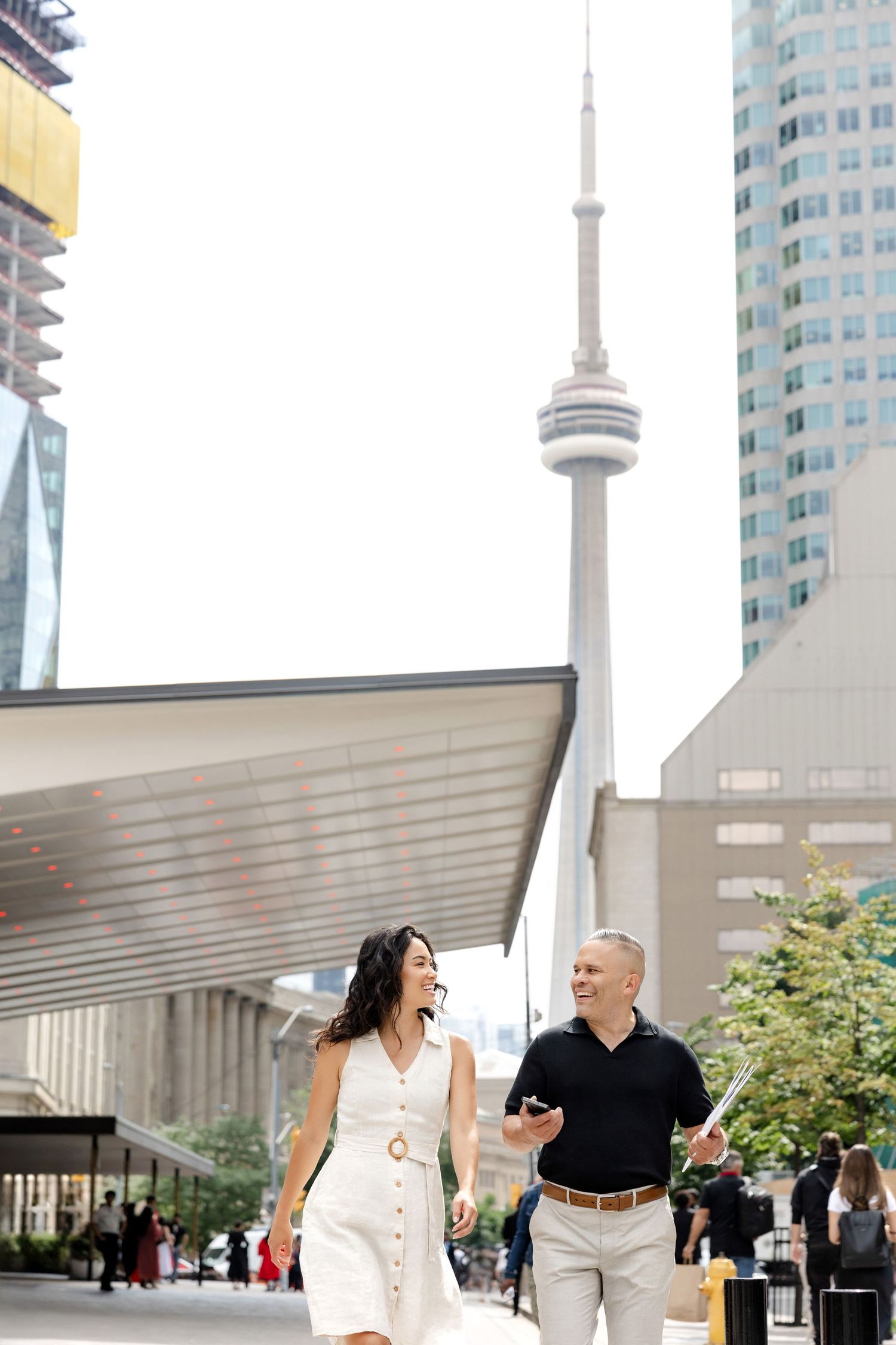 People walking near modern buildings with the CN Tower visible in downtown Toronto.