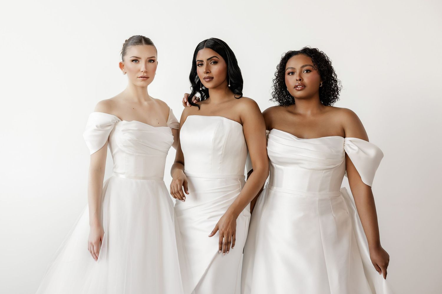 Three models display contemporary white wedding gowns with architectural details.