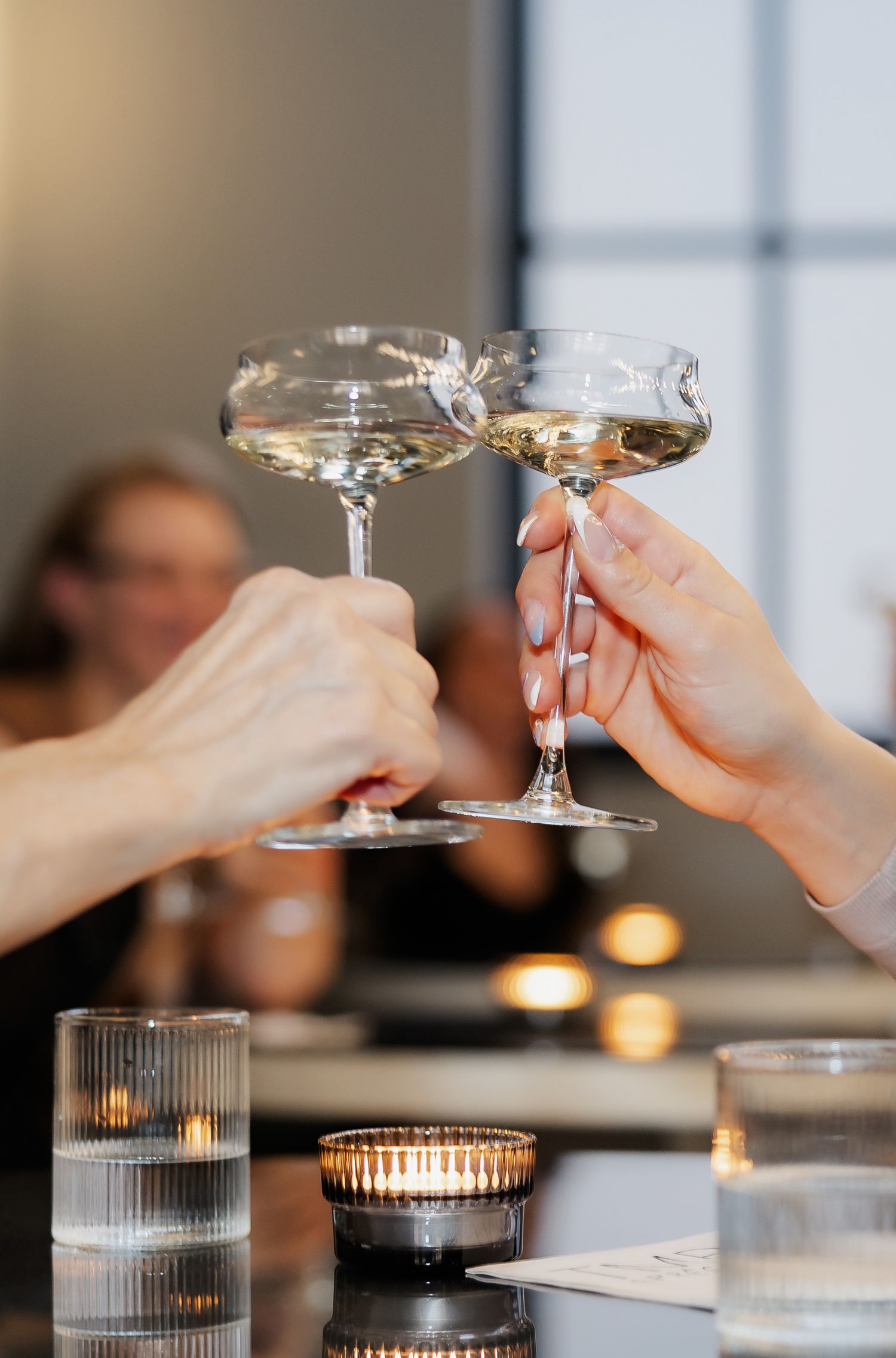 Elegant champagne glasses clinking over candlelit table during a celebration.