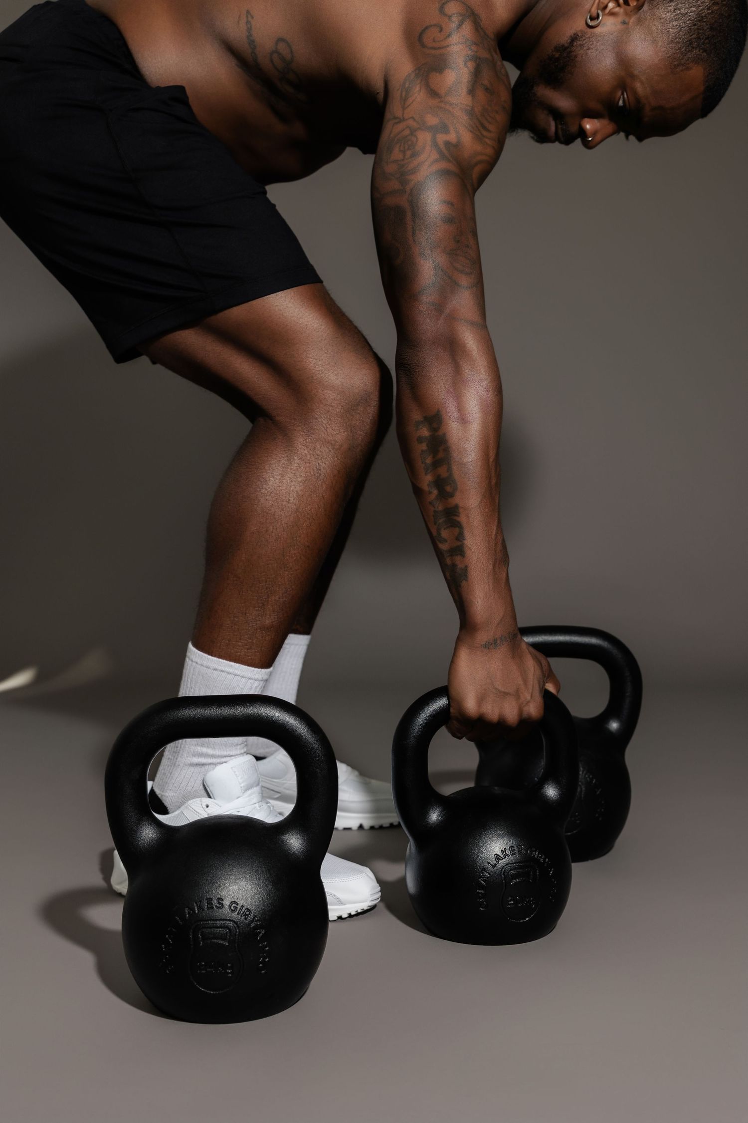 Low angle view of athlete gripping two kettlebells during workout.