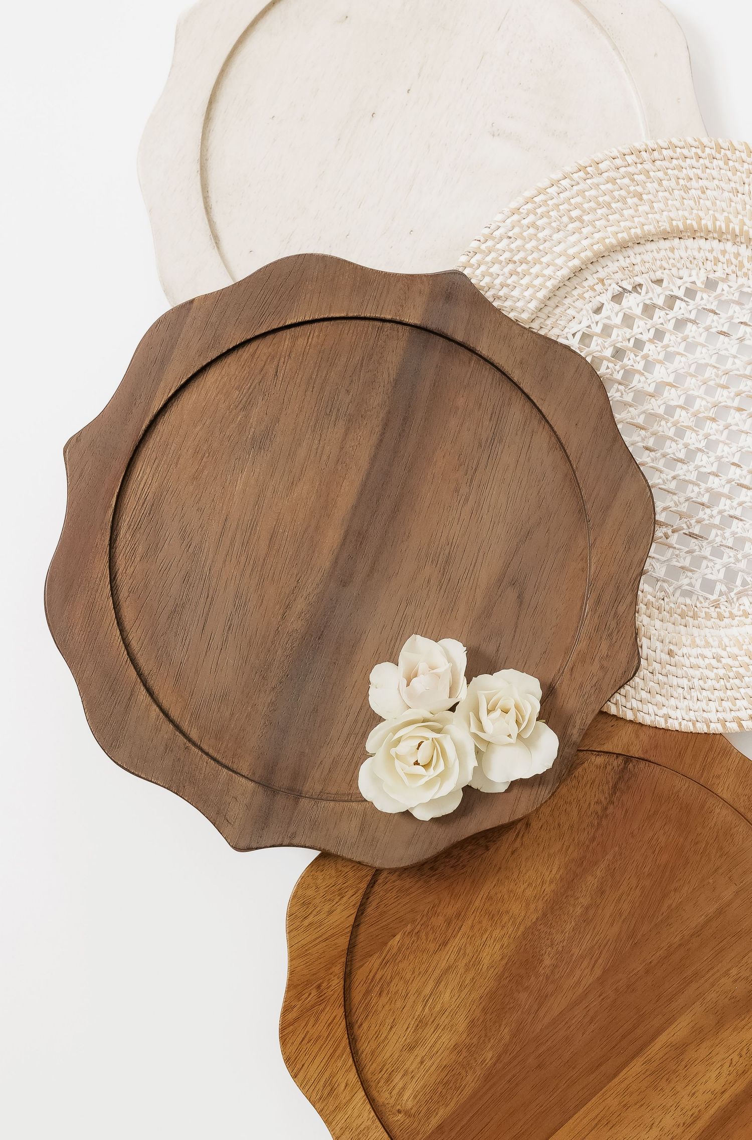 Scalloped wooden charger plates with white floral accents and woven placemats.
