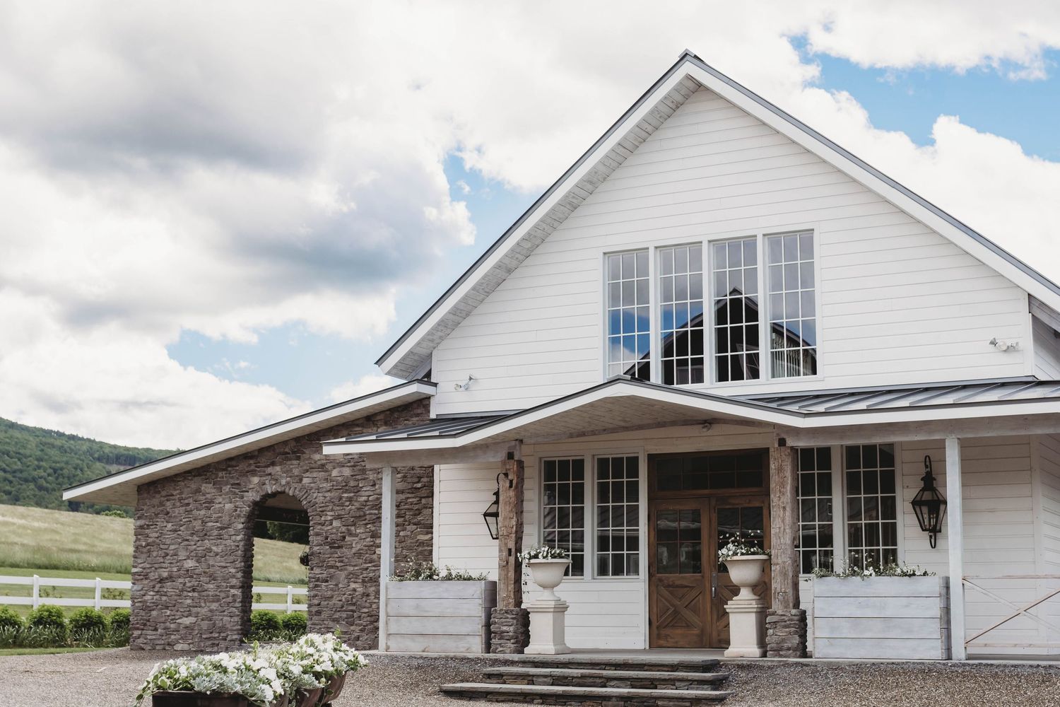 Wedding venue exterior with white siding and large windows, photographed for a romantic wedding celebration by a wedding photographer.