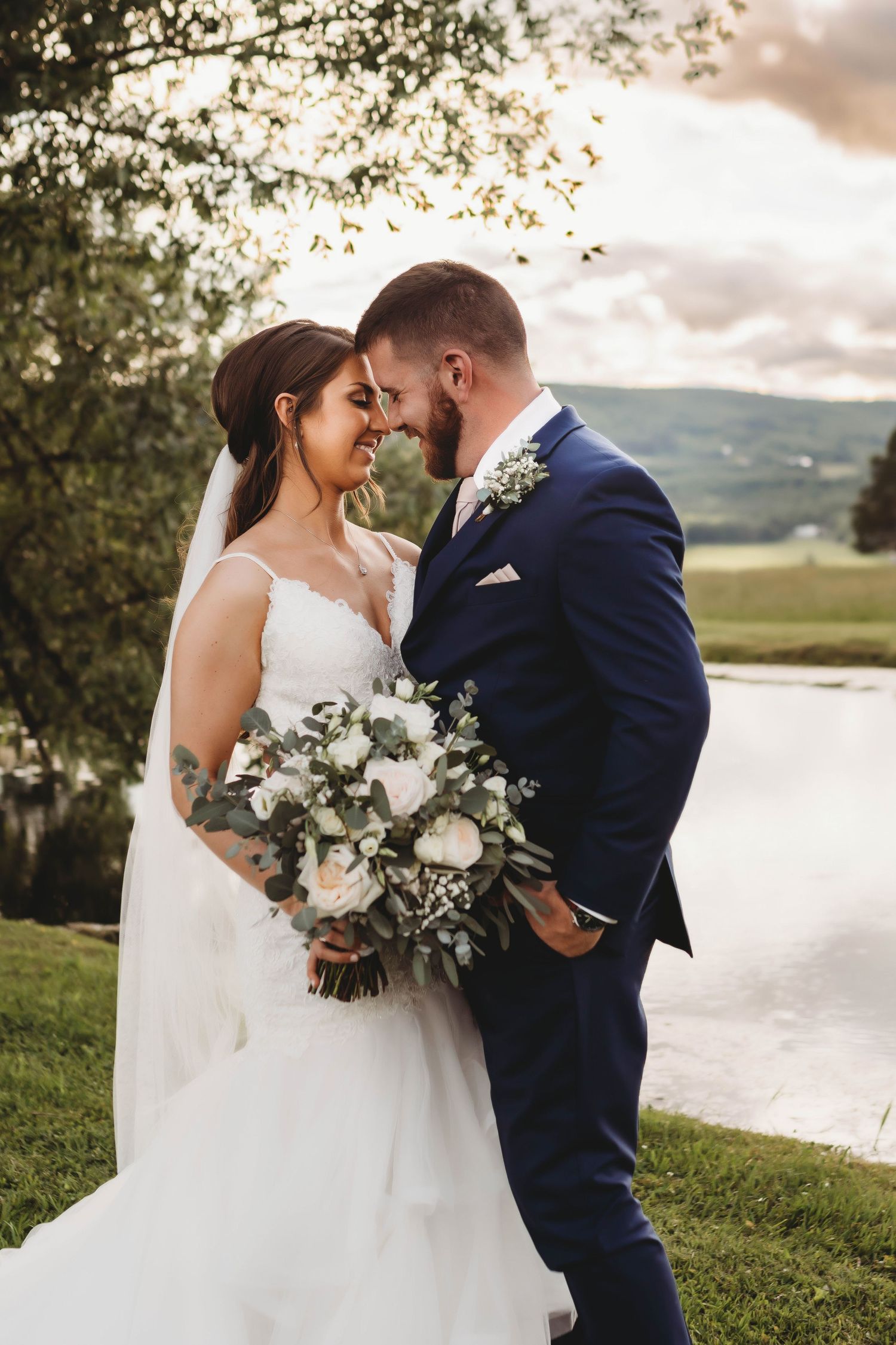 Newlyweds sharing an intimate moment by a lake during golden hour.