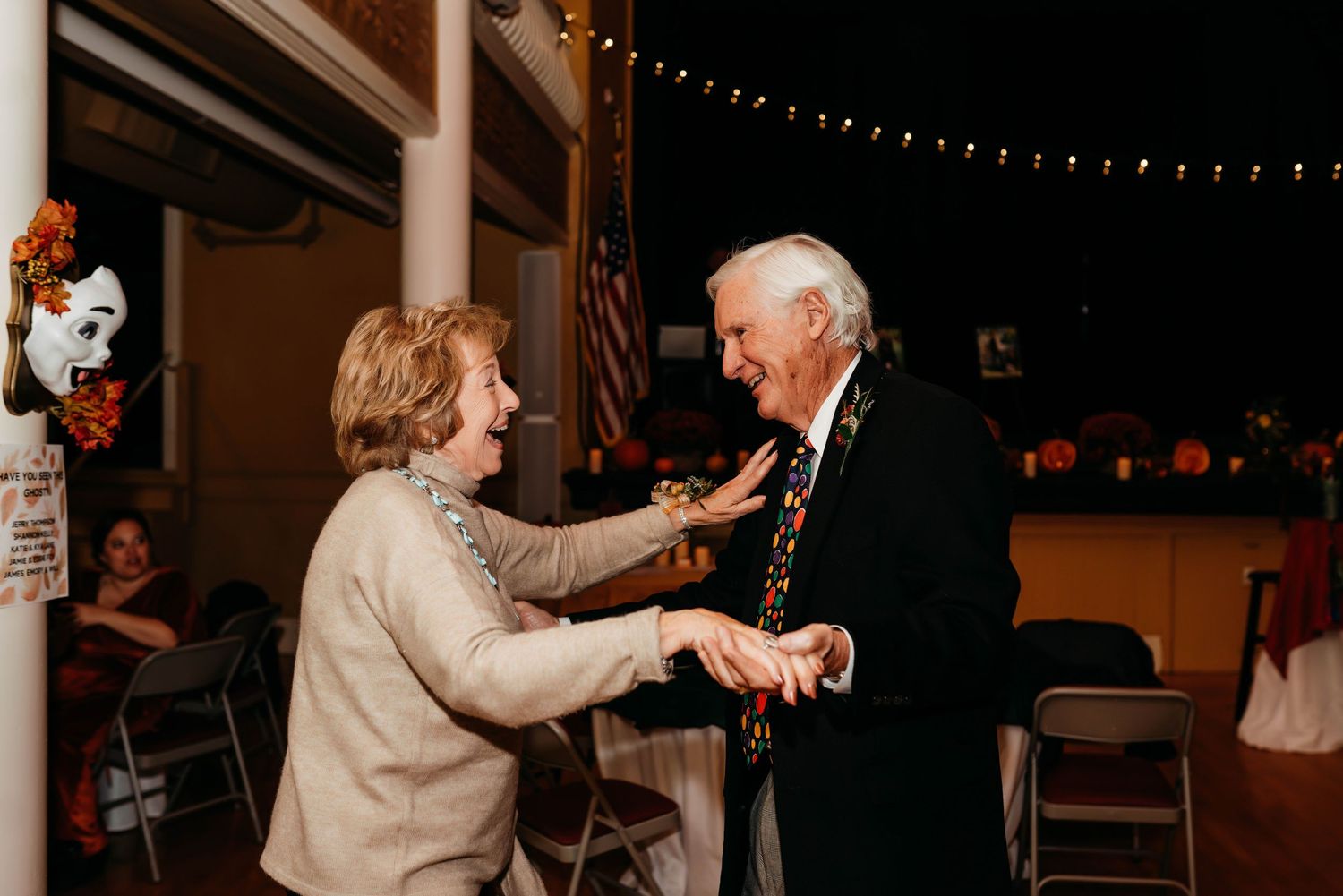 Wedding guests dancing together during a reception decorated with warm string lights.