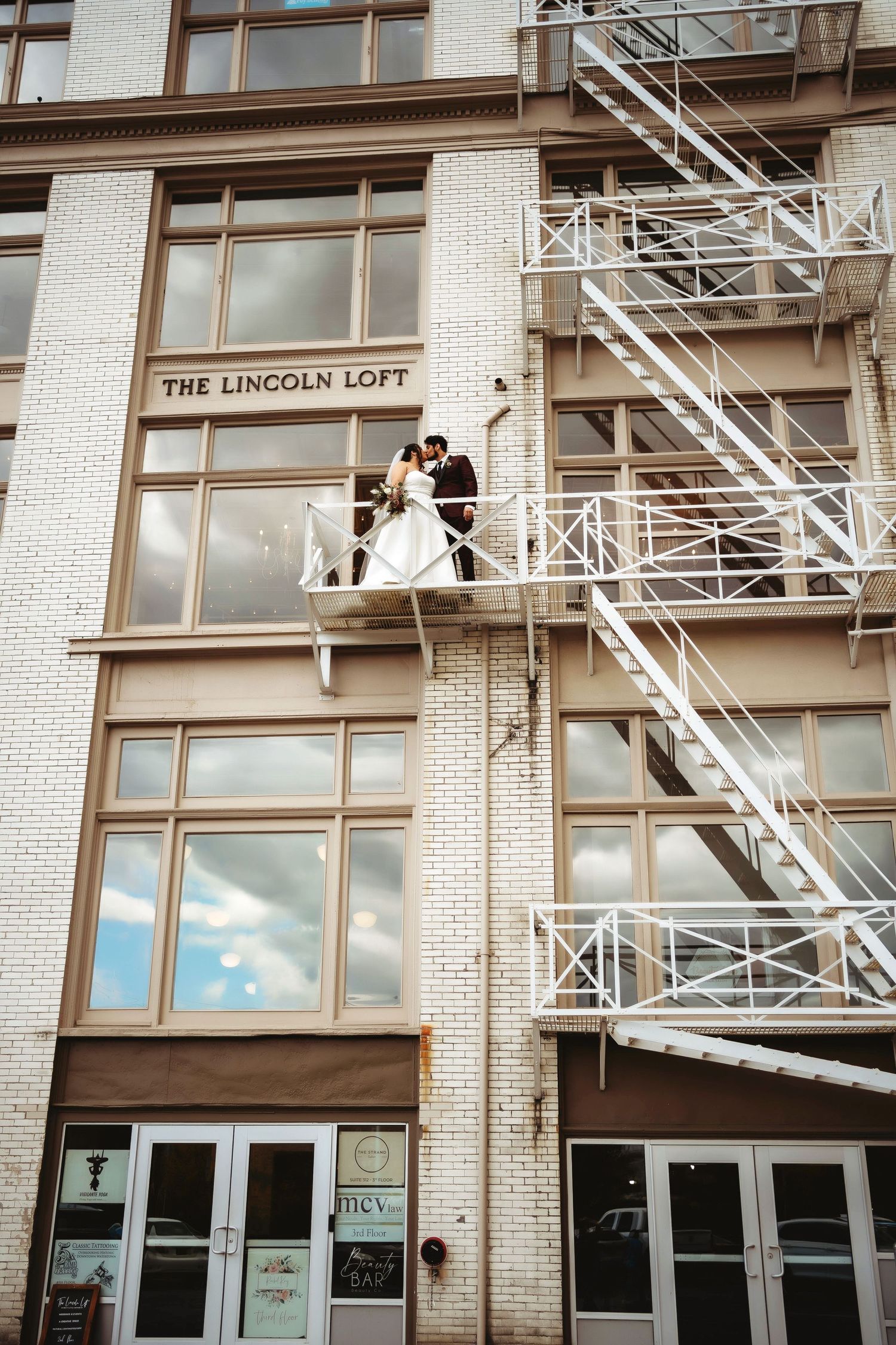 Couple sharing a romantic moment on a balcony, captured in an editorial- style wedding photograph.