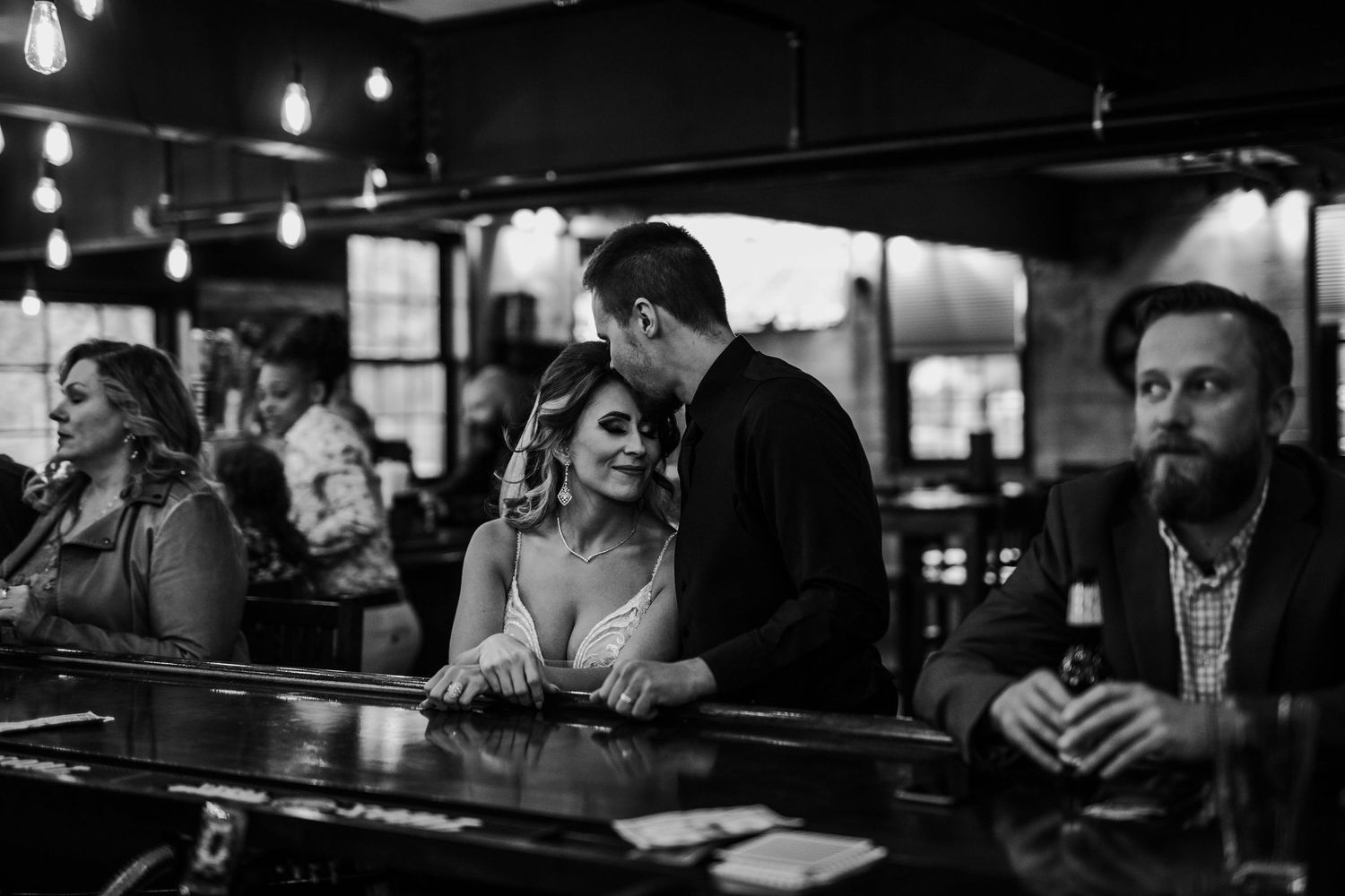 Bride and groom share a romantic moment at a bar after their wedding ceremony.