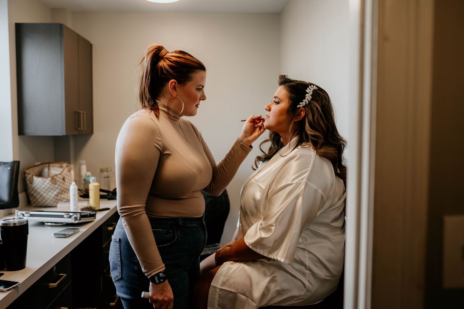 An authentic- documentary style shot of the bride getting her makeup done by an MUA.