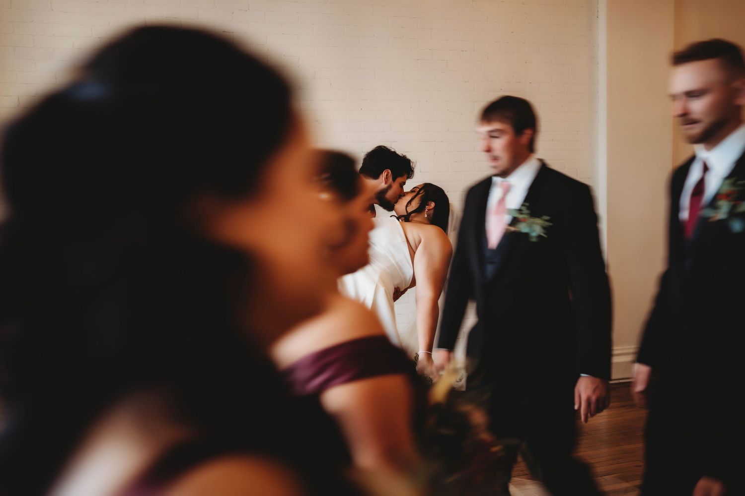 Candid wedding ceremony moment with guests and groomsmen in formal attire, captured in a documentary wedding photography style.