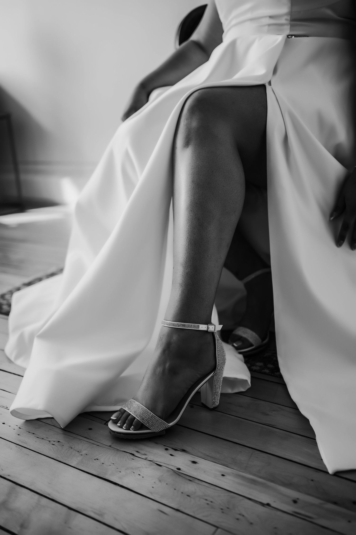 Black and white detail shots of wedding dress fabric flowing across wooden floor, captured in an editorial style.