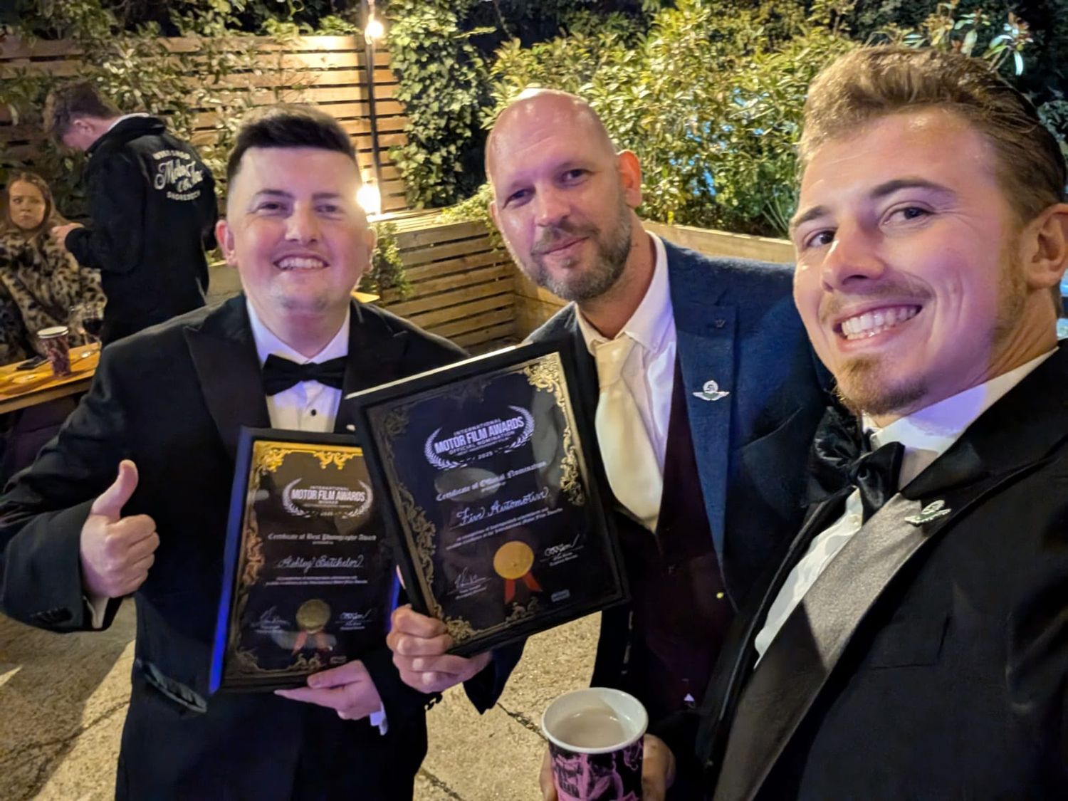 A group celebrates at an evening event with smiles and formal attire at what appears to be an awards ceremony.