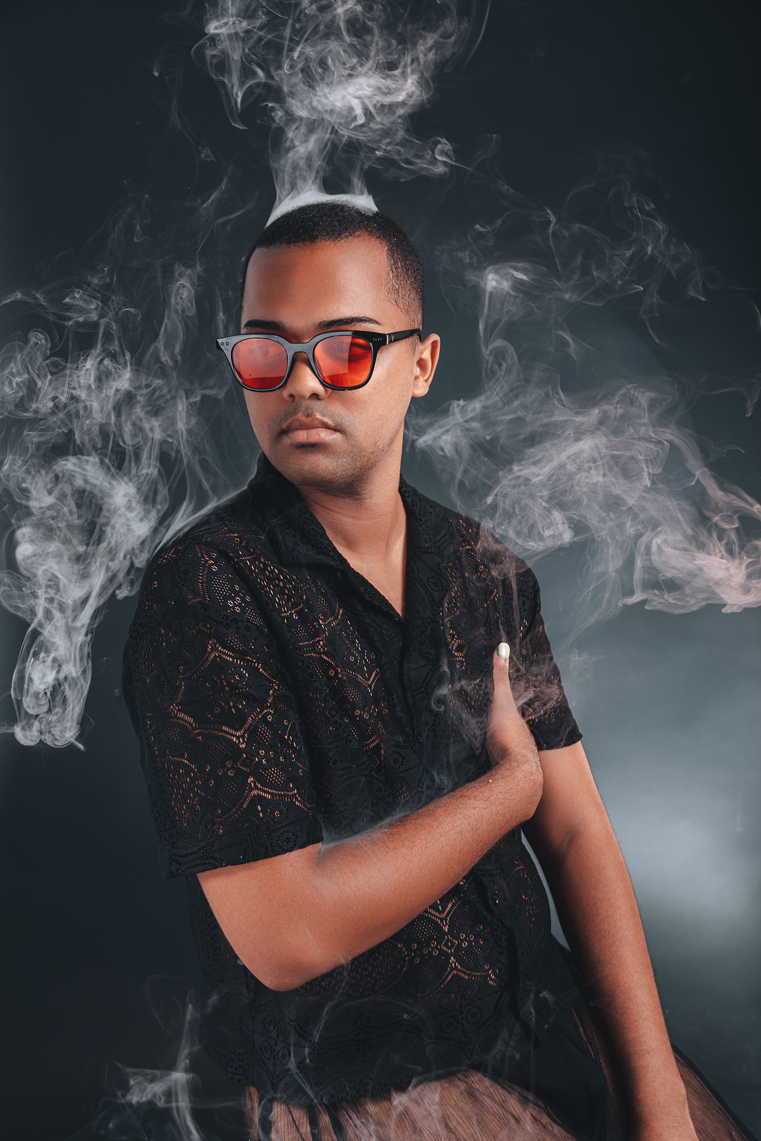 Creative studio portrait of a male performer surrounded by atmospheric smoke and dramatic lighting effects.