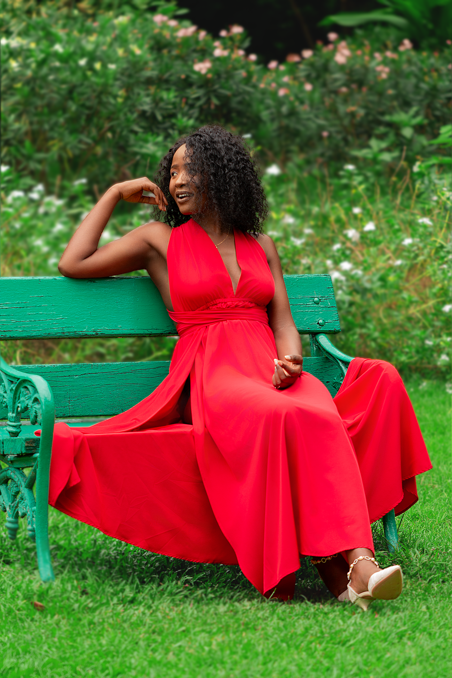 Creative outdoor portrait of a woman in a red dress seated in nature, photographed with soft natural light and vibrant colors.