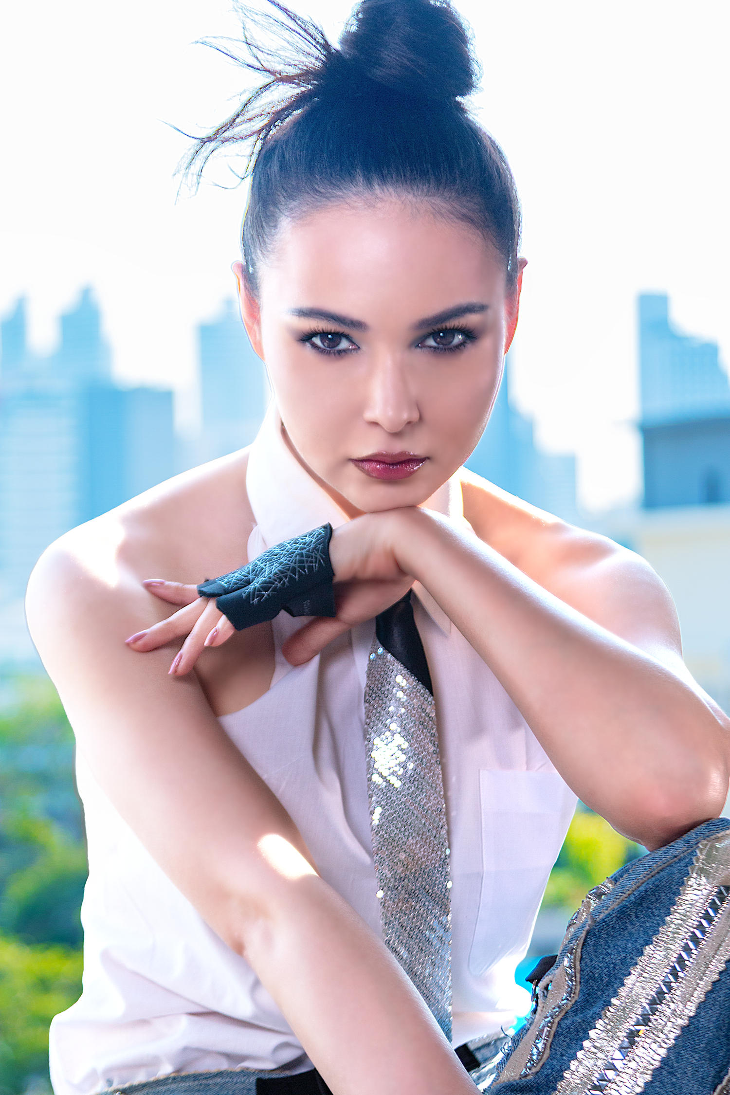 Professional beauty portrait featuring a female model photographed outdoors with natural light and city skyline views.