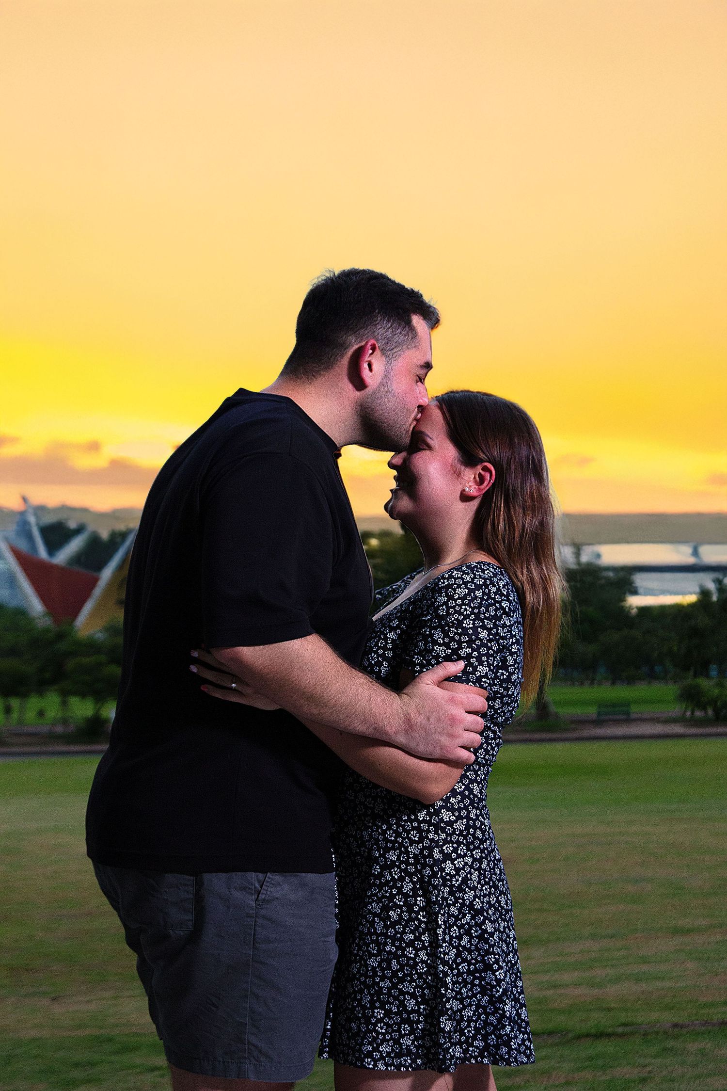 Professional engagement photography featuring a couple embracing during sunset with natural outdoor scenery.