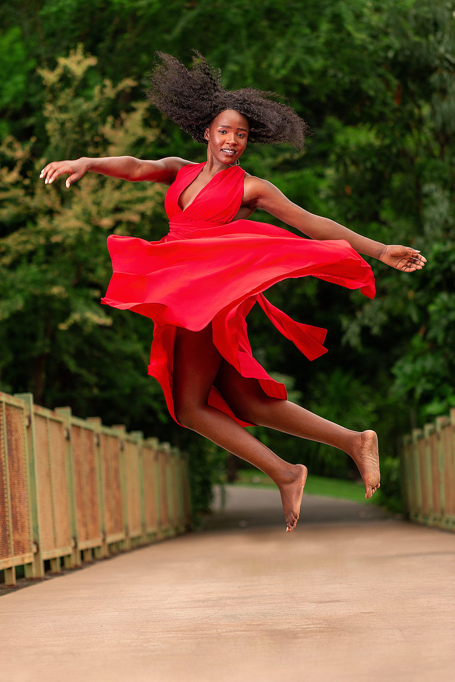 Creative outdoor portrait photography featuring a woman in a flowing red dress captured with movement and natural scenery.