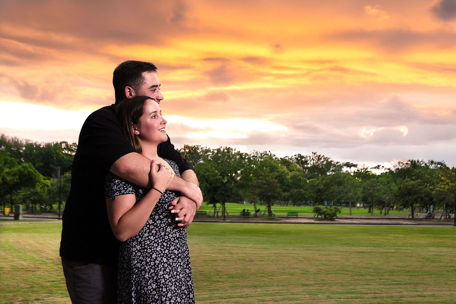Romantic couples photography featuring an engaged couple embracing outdoors during a dramatic sunset session in Bangkok.