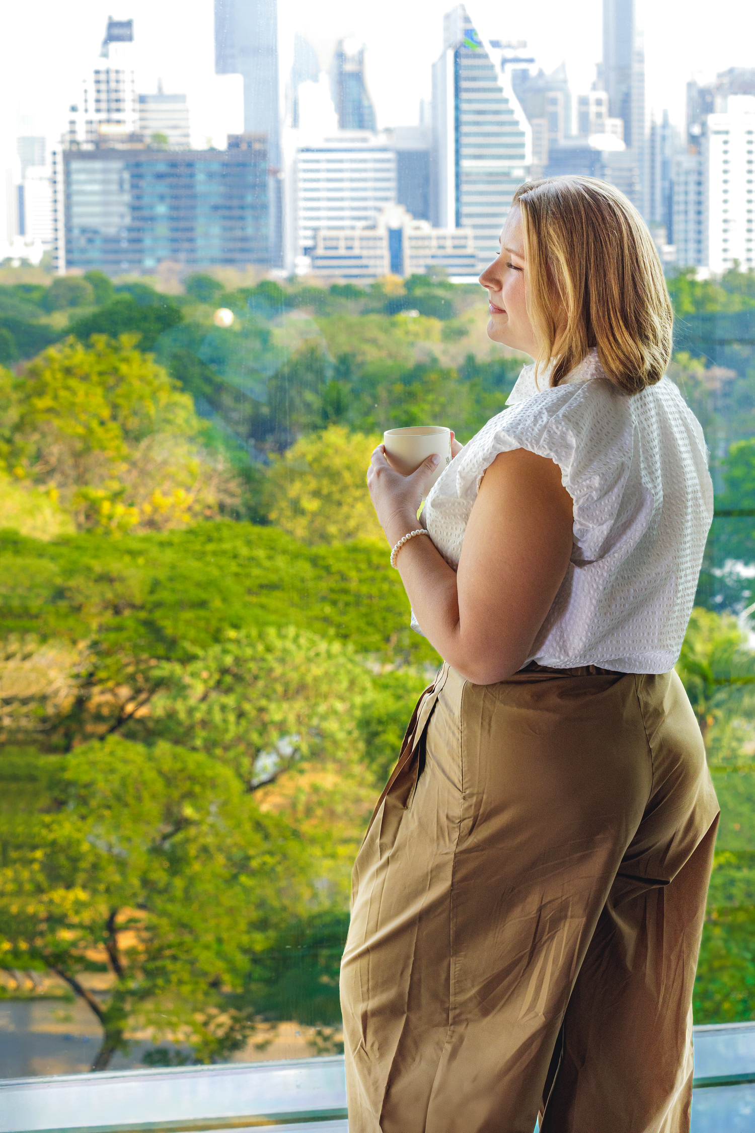 Professional branding portrait of a woman overlooking Bangkok's city skyline during an outdoor photoshoot.