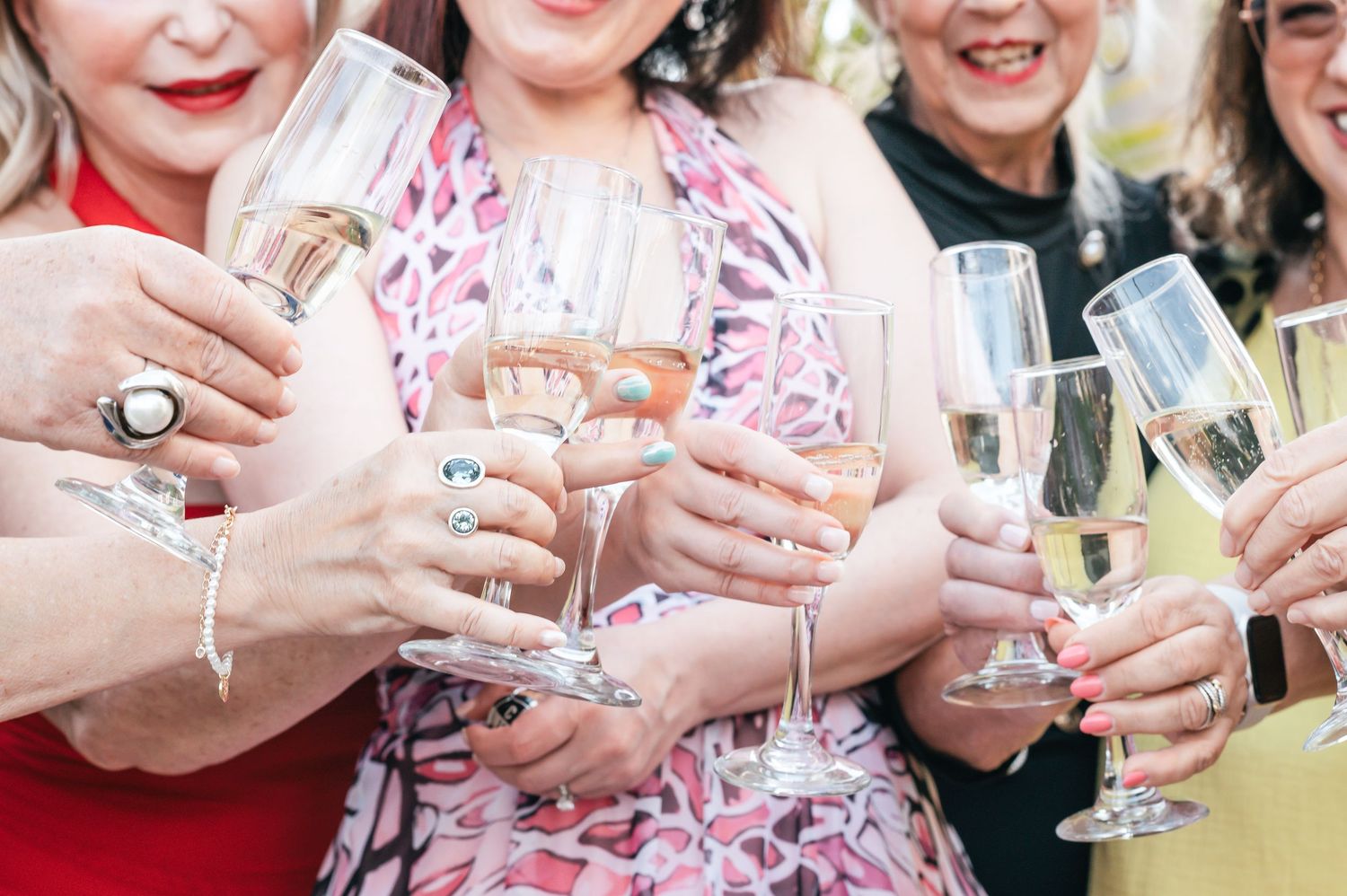 Group of people toasting with champagne glasses at outdoor celebration.