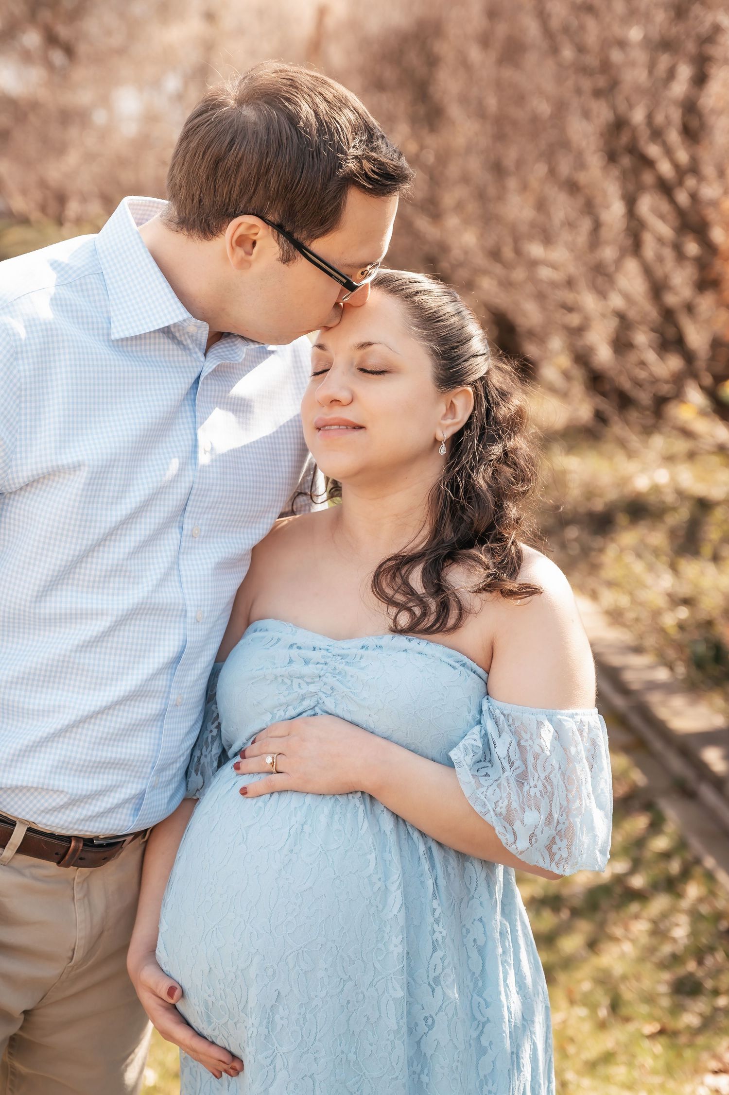 Intimate maternity photos of couple in blue lace dress outdoors.