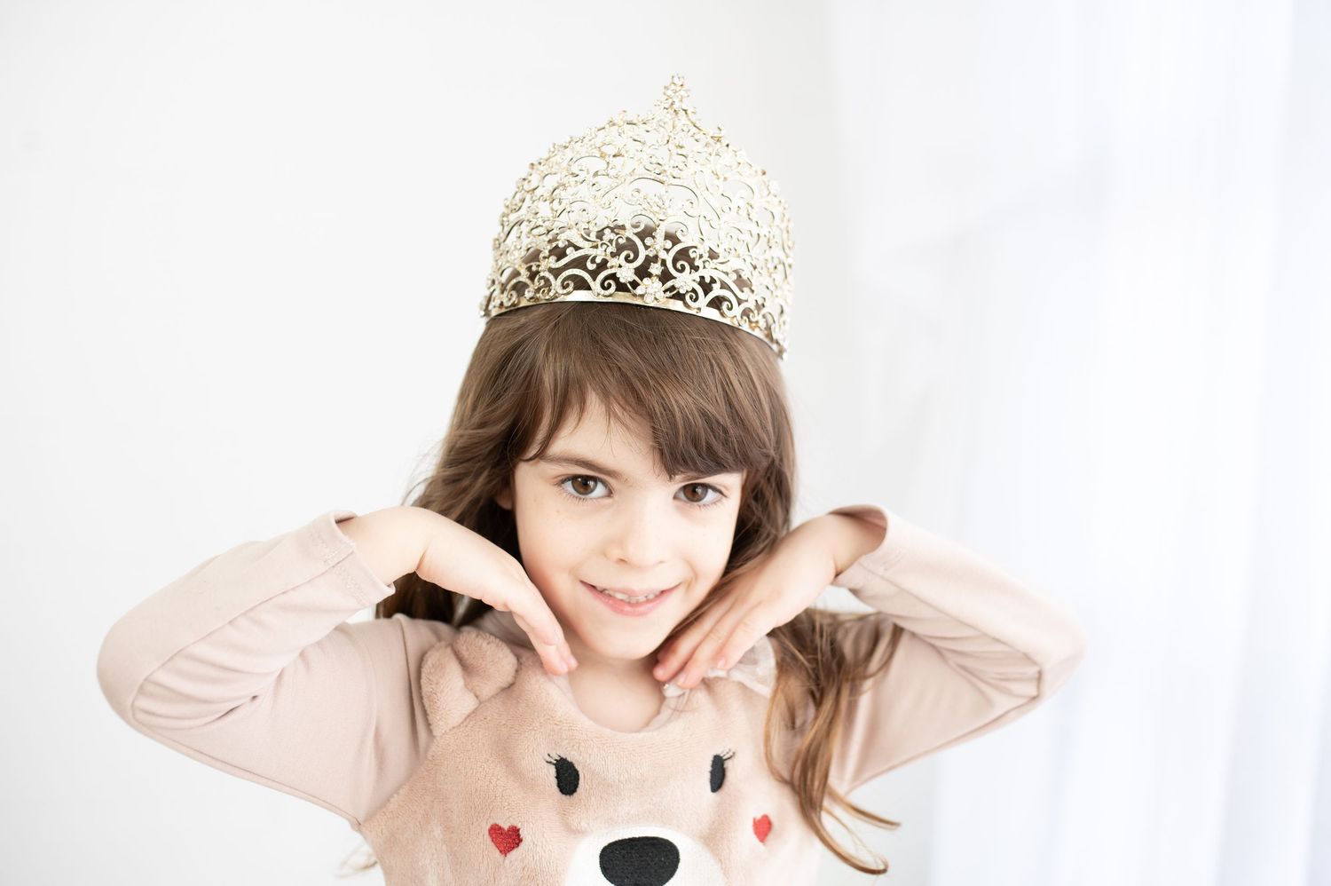 Woman in lace hat posing playfully against white background.