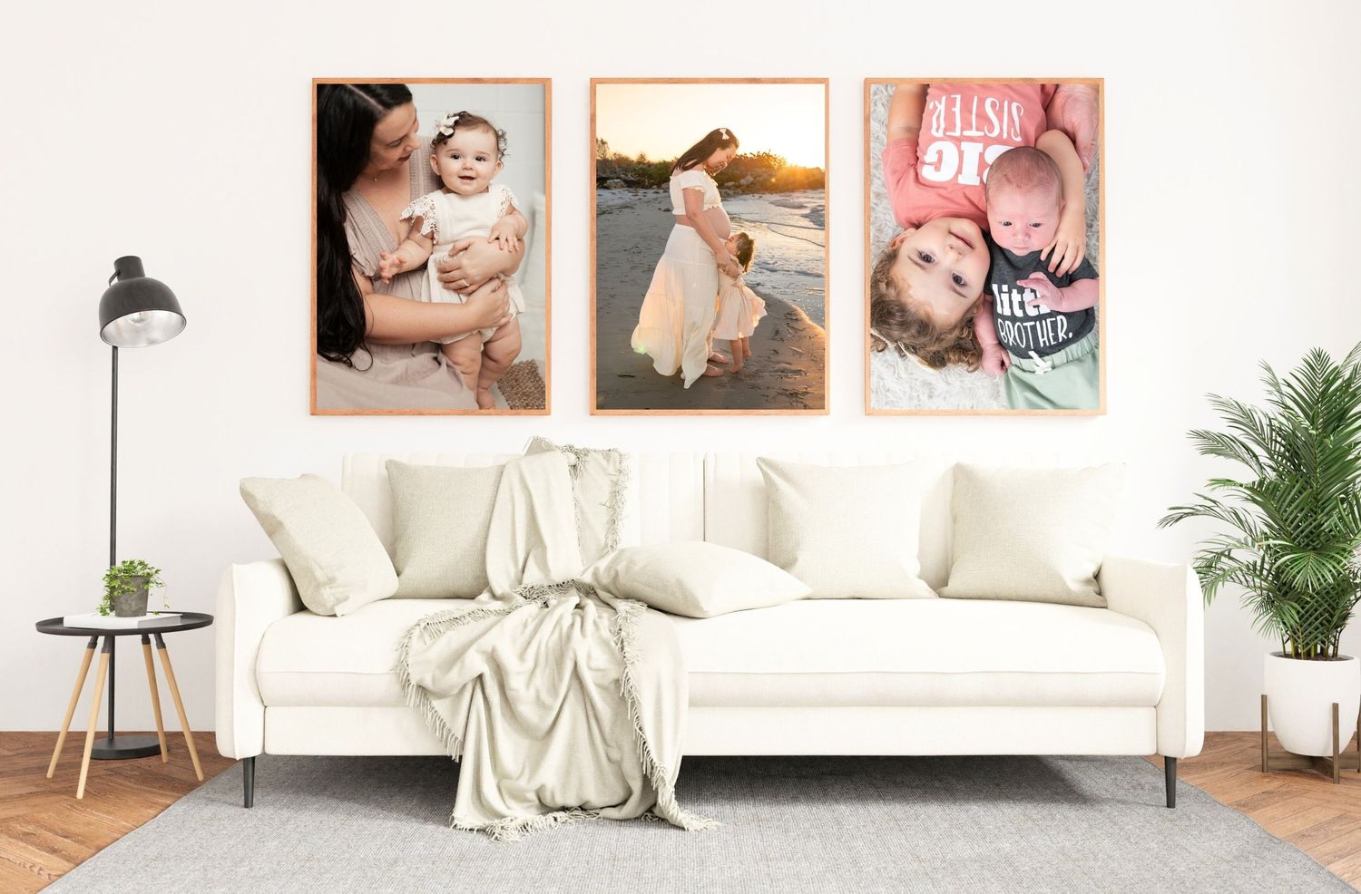 Three framed family photos of babies and mothers displayed above a white sofa in a bright modern living room.