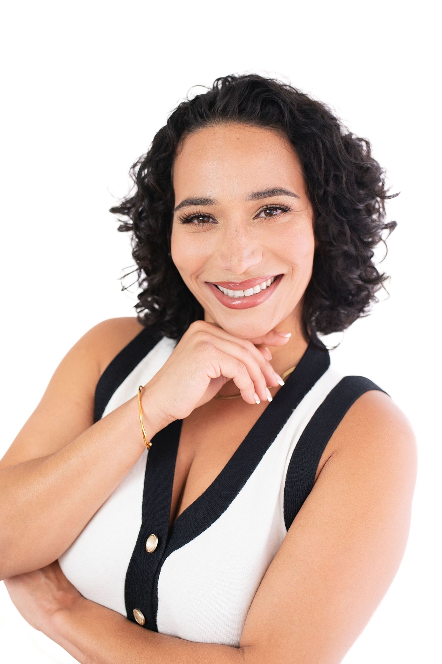 Studio portraits of woman in black and white outfit with curly hair.
