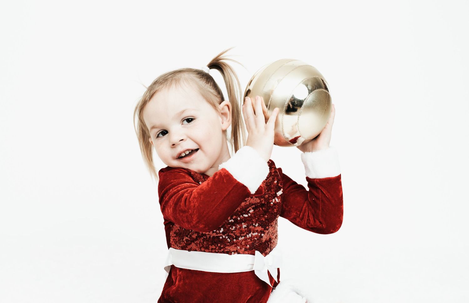 Festive holiday portraits of a child in red dress against white background.
