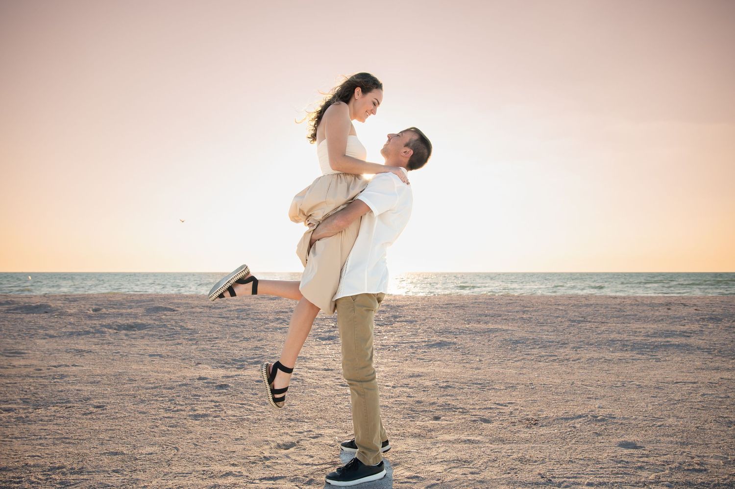 Couple sharing intimate moments on beach during sunset photoshoot.